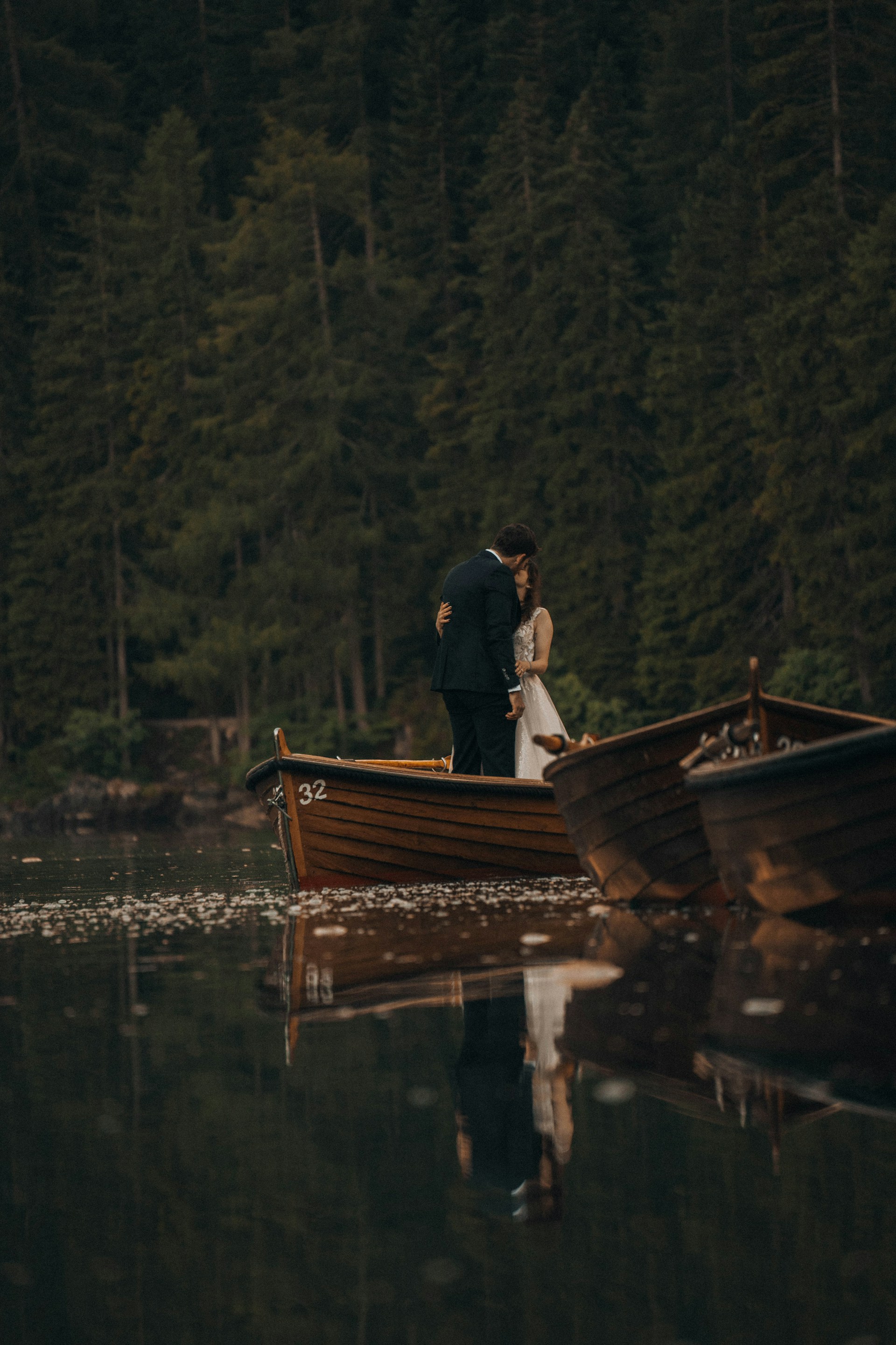 Couple embraces intimately on a boat in a lake.