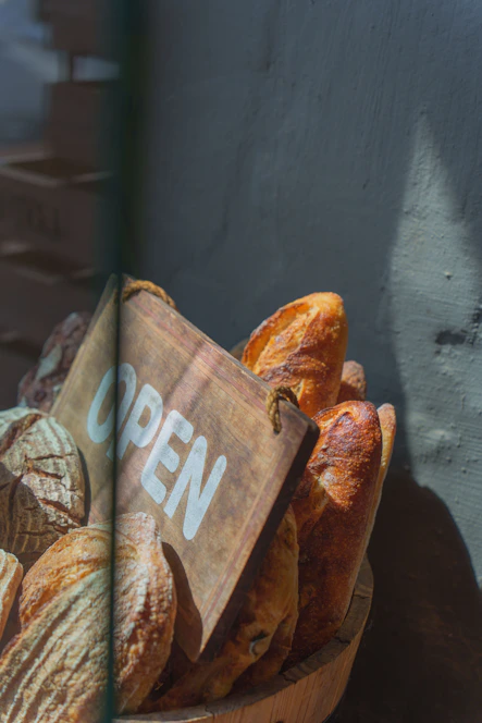 Fresh bread is displayed next to an open sign.