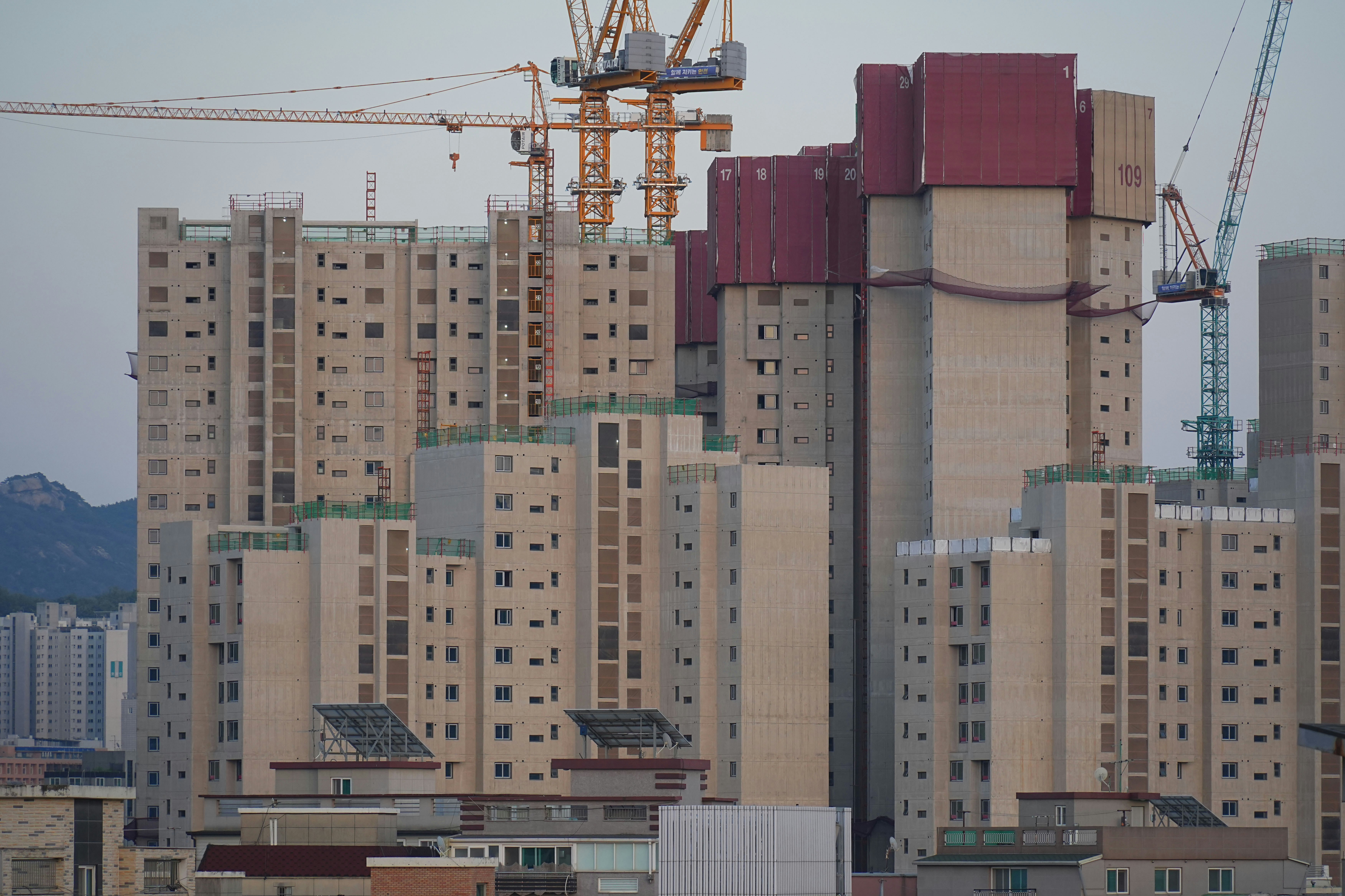 Buildings are under construction with tower cranes.