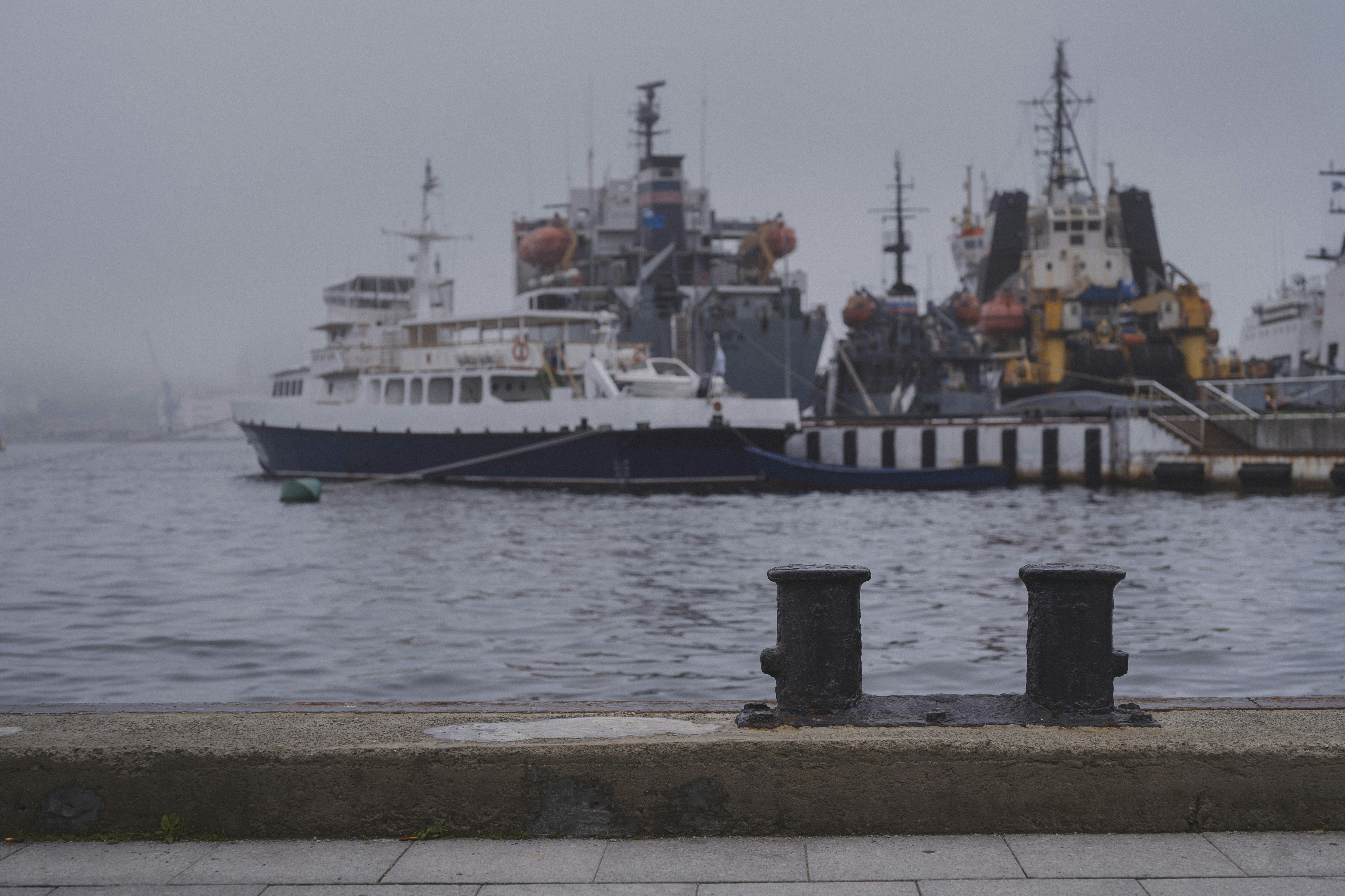 Ships are docked in the harbor on a cloudy day.