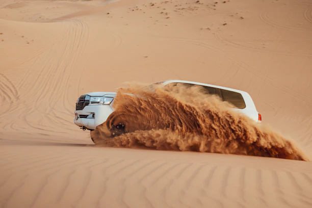 A car kicks up sand in the desert