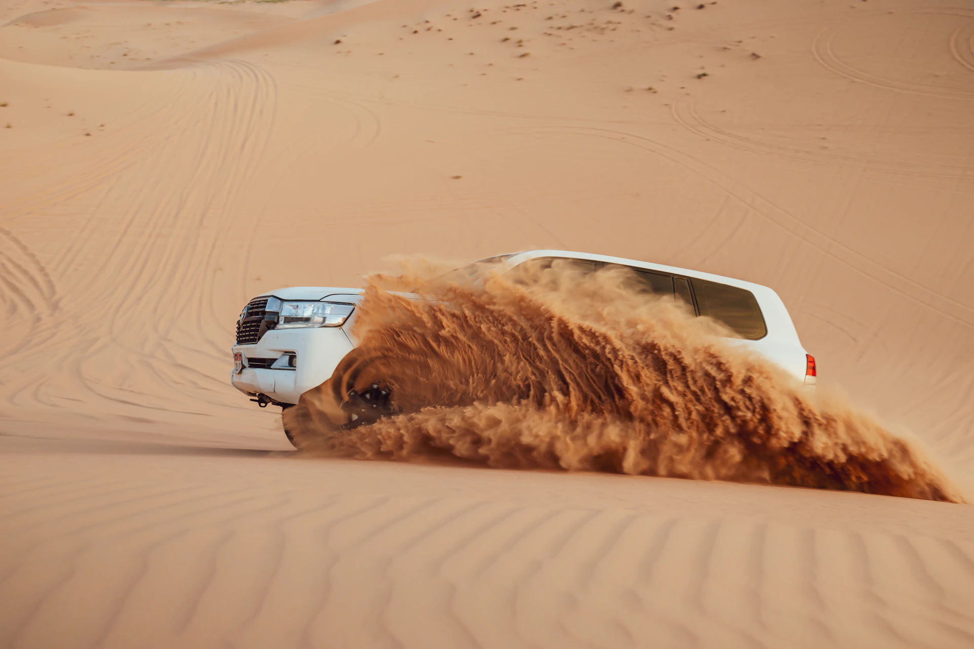 A four wheel drive throwing a wall of sand while dune bashing