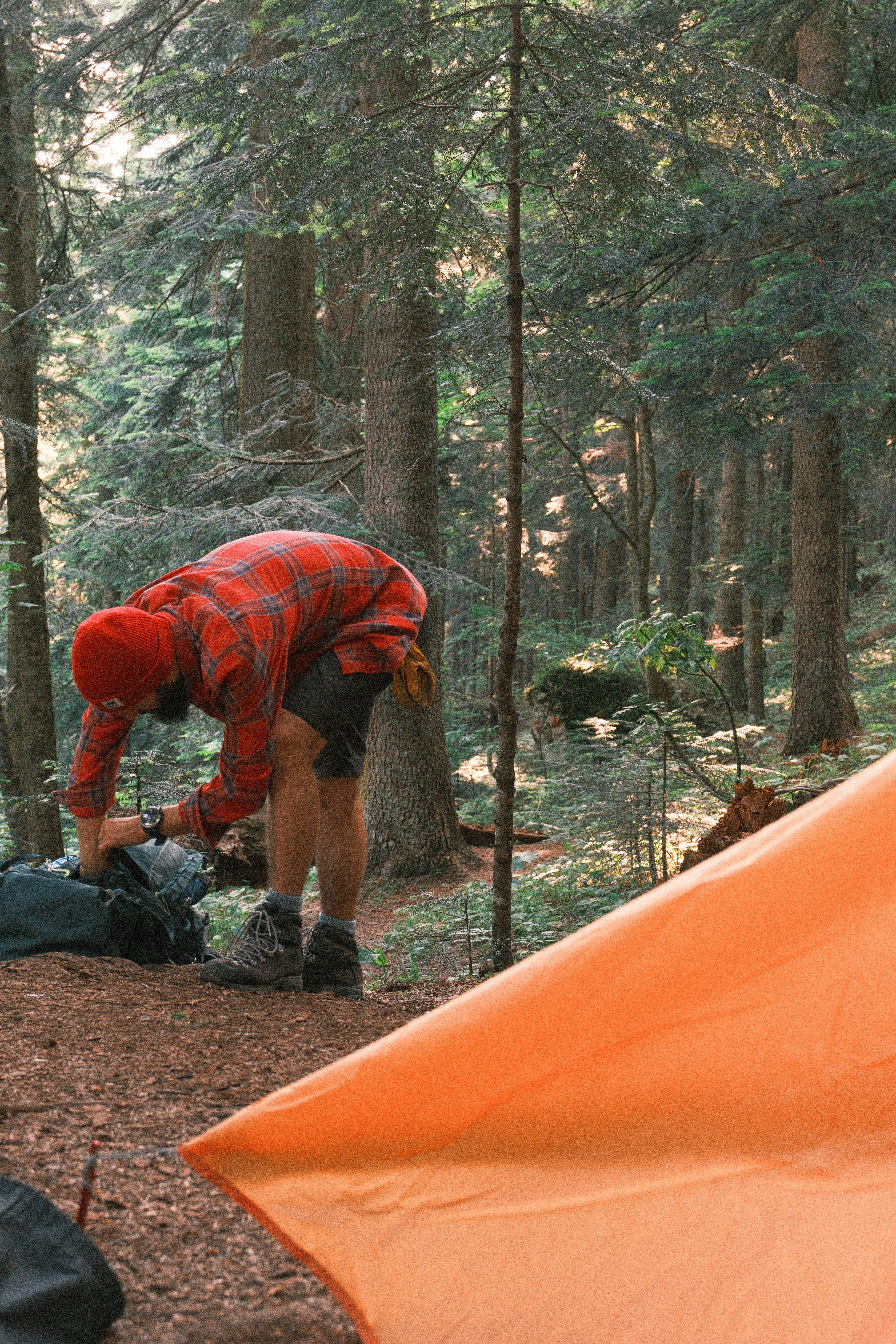 Man packs his backpack in a forest.