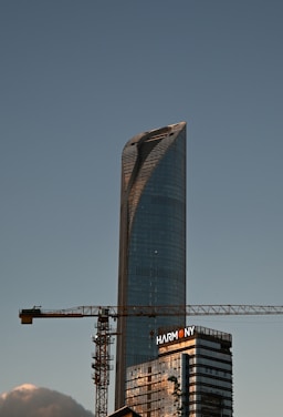 A tall skyscraper is under construction with a crane.