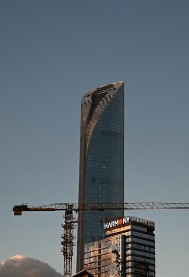 A tall skyscraper is under construction with a crane.