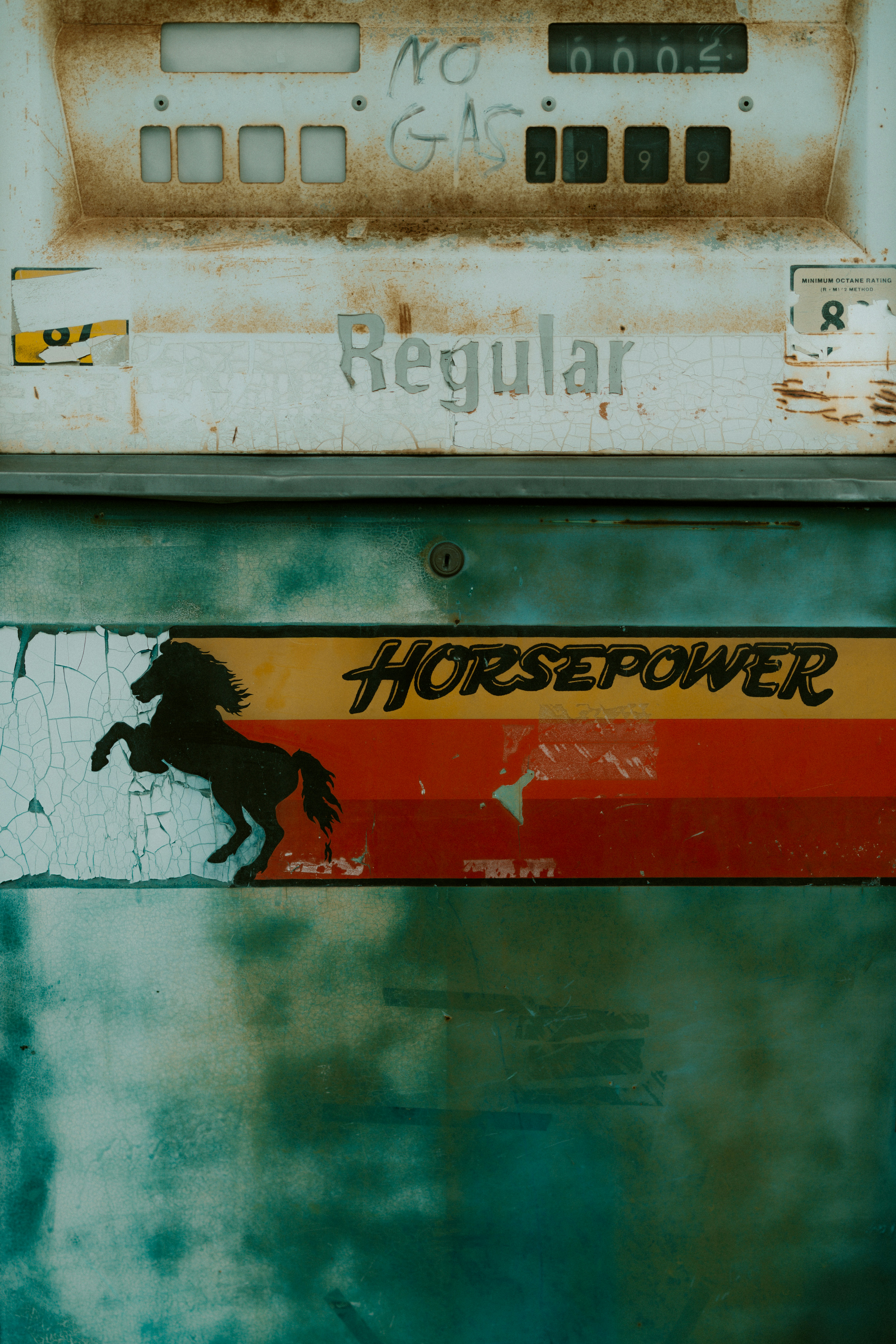 Alte, verwitterte Zapfsäule mit Pferdegrafik.