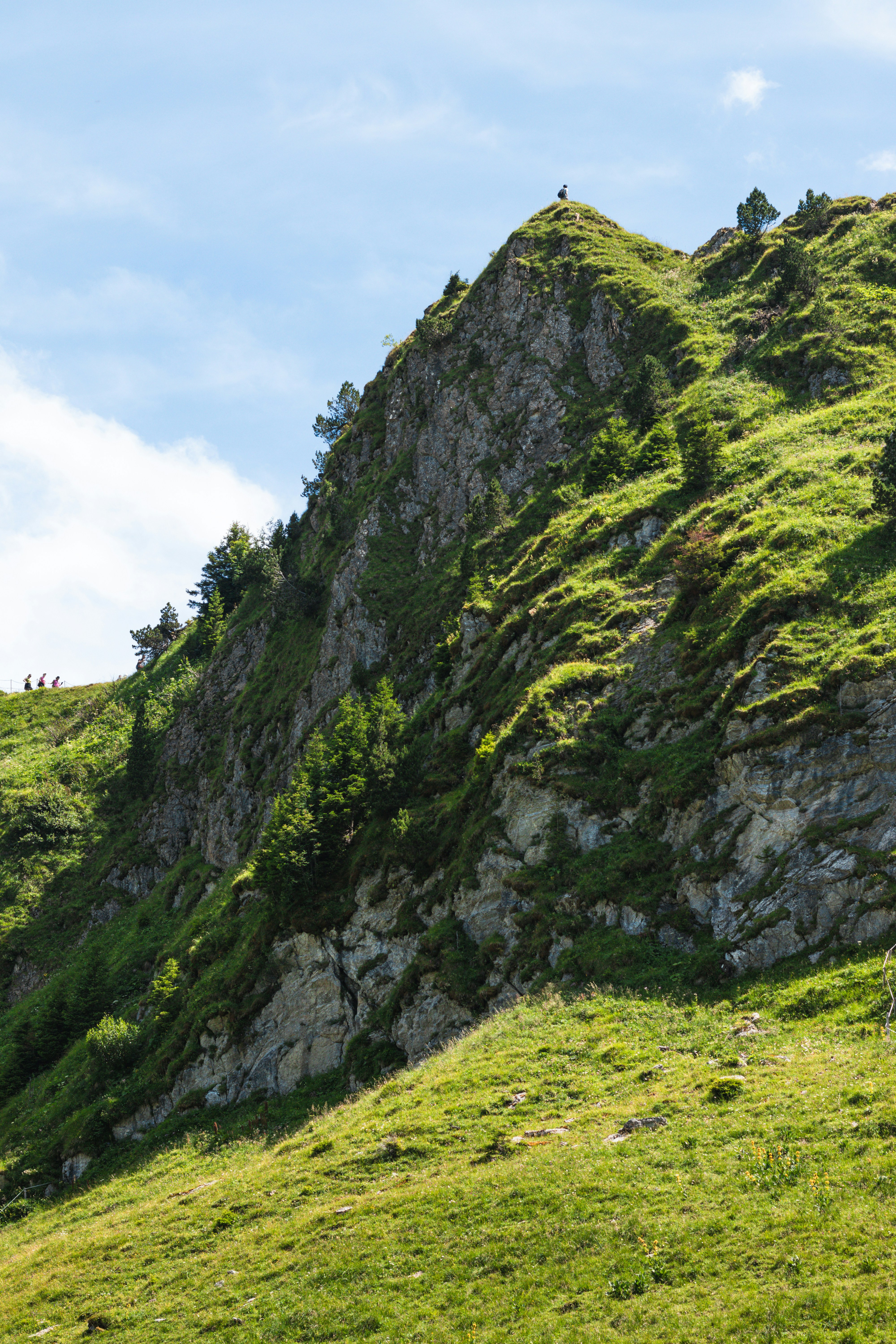 A green mountain slopes up against a bright sky.
