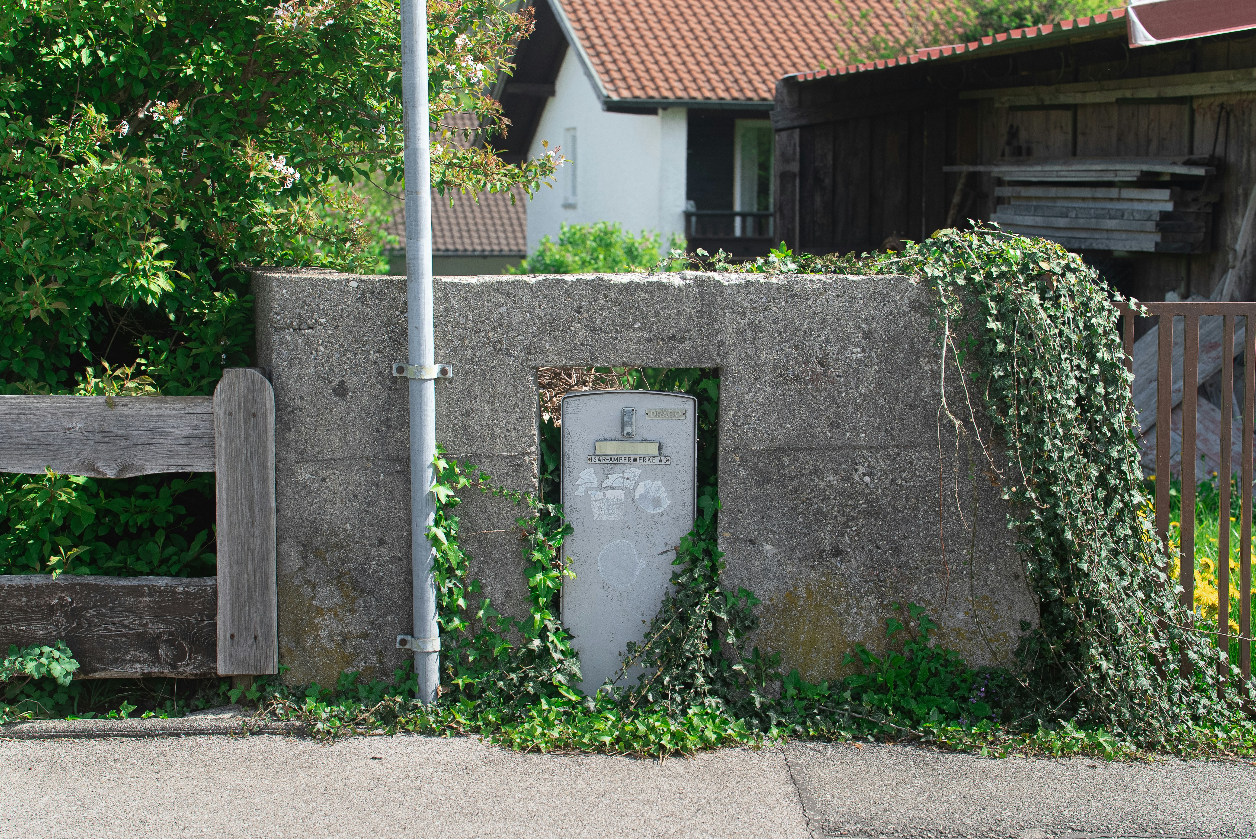 A stone fence with a post covered in vines.