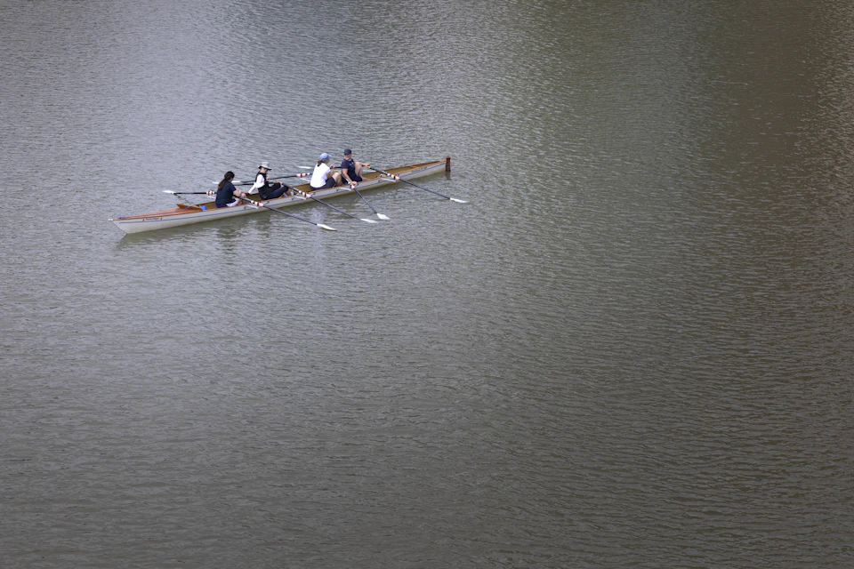 Four women rowing together across calm water