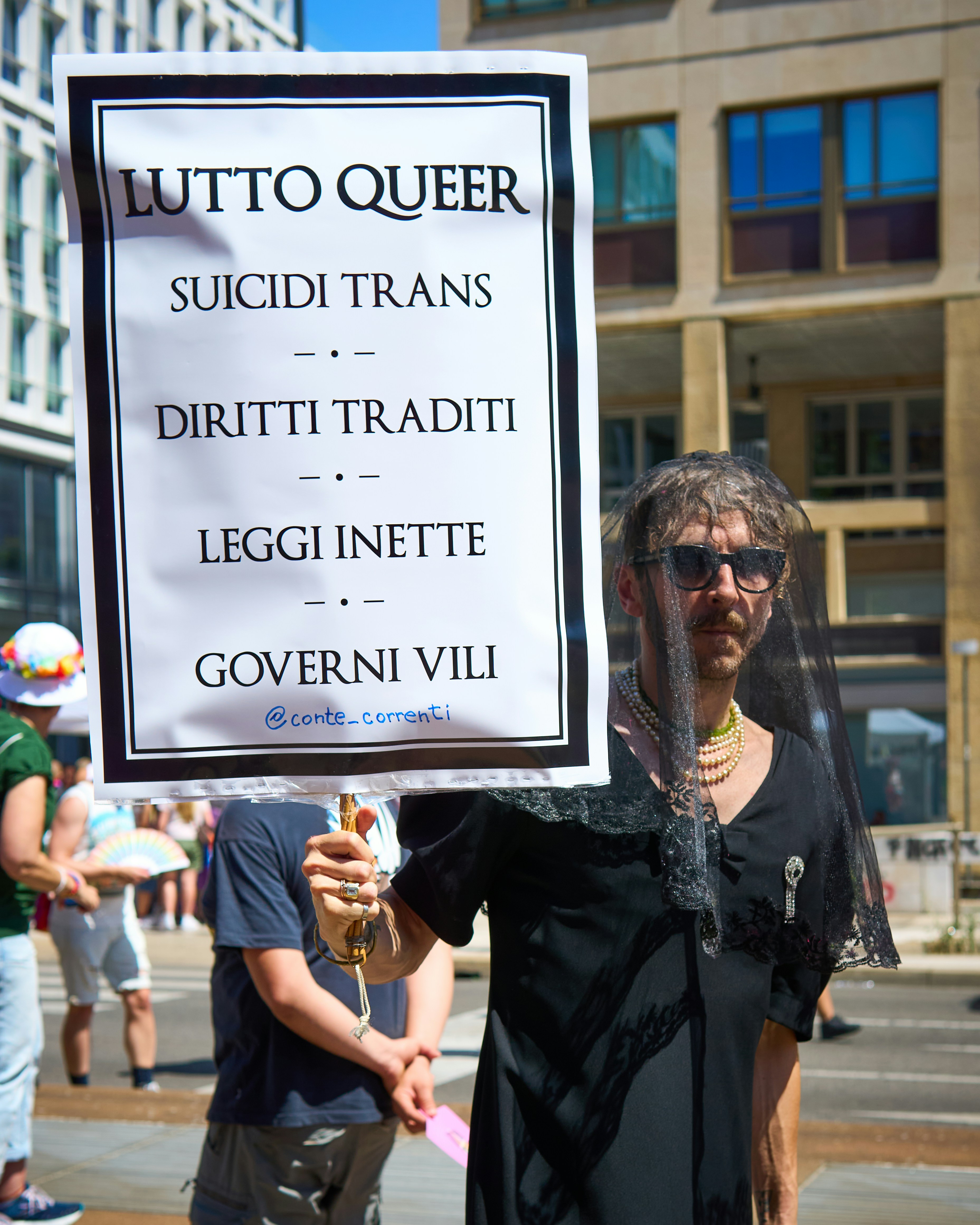 Protester holds a sign about queer grief and rights.