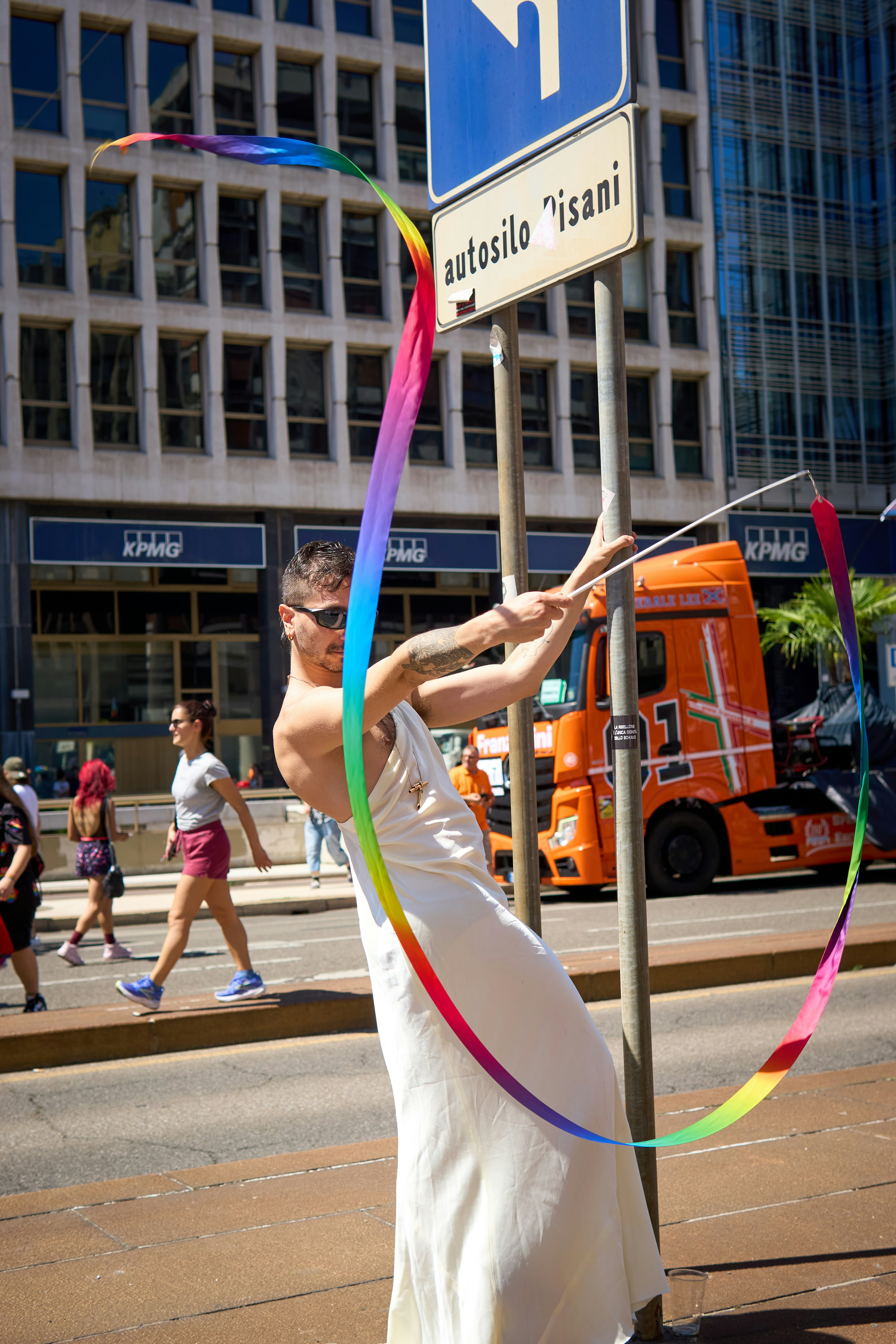 A man performs with a rainbow ribbon at a parade.