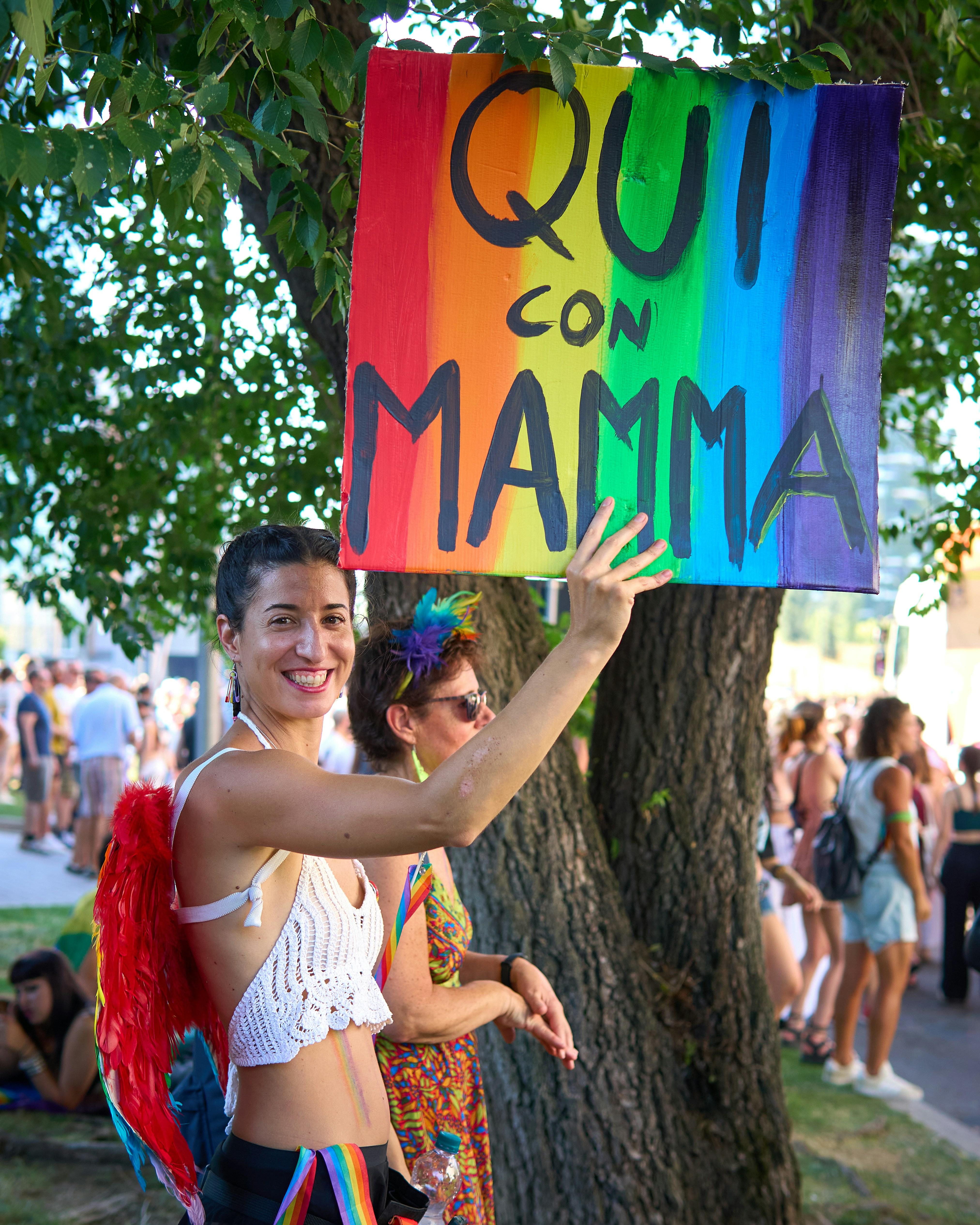Woman at pride event holds up a rainbow sign.