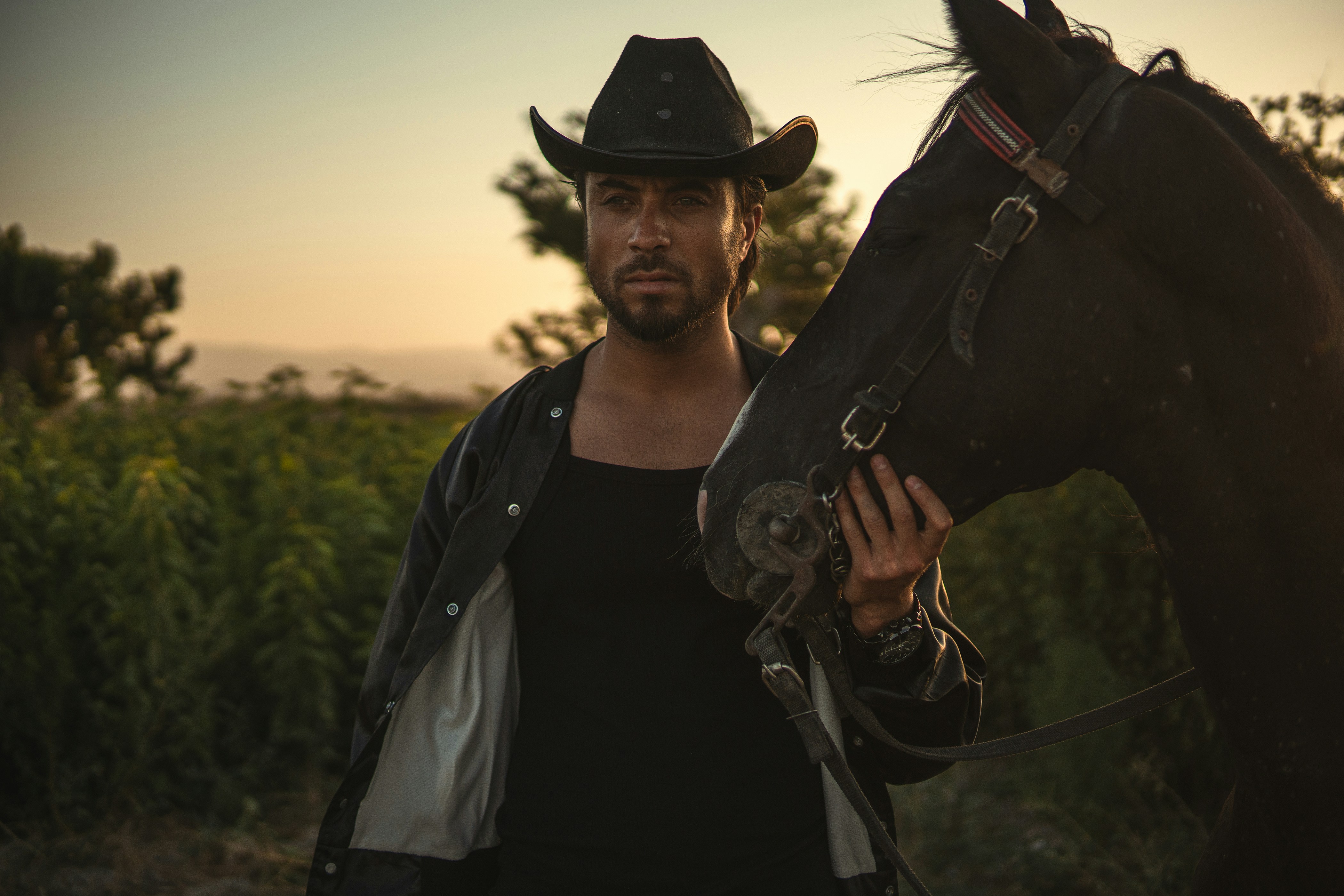 Cowboy and horse pose outdoors at sunset.