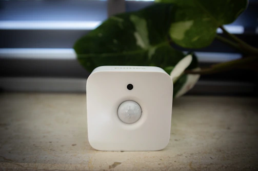A white sensor sits in front of foliage.