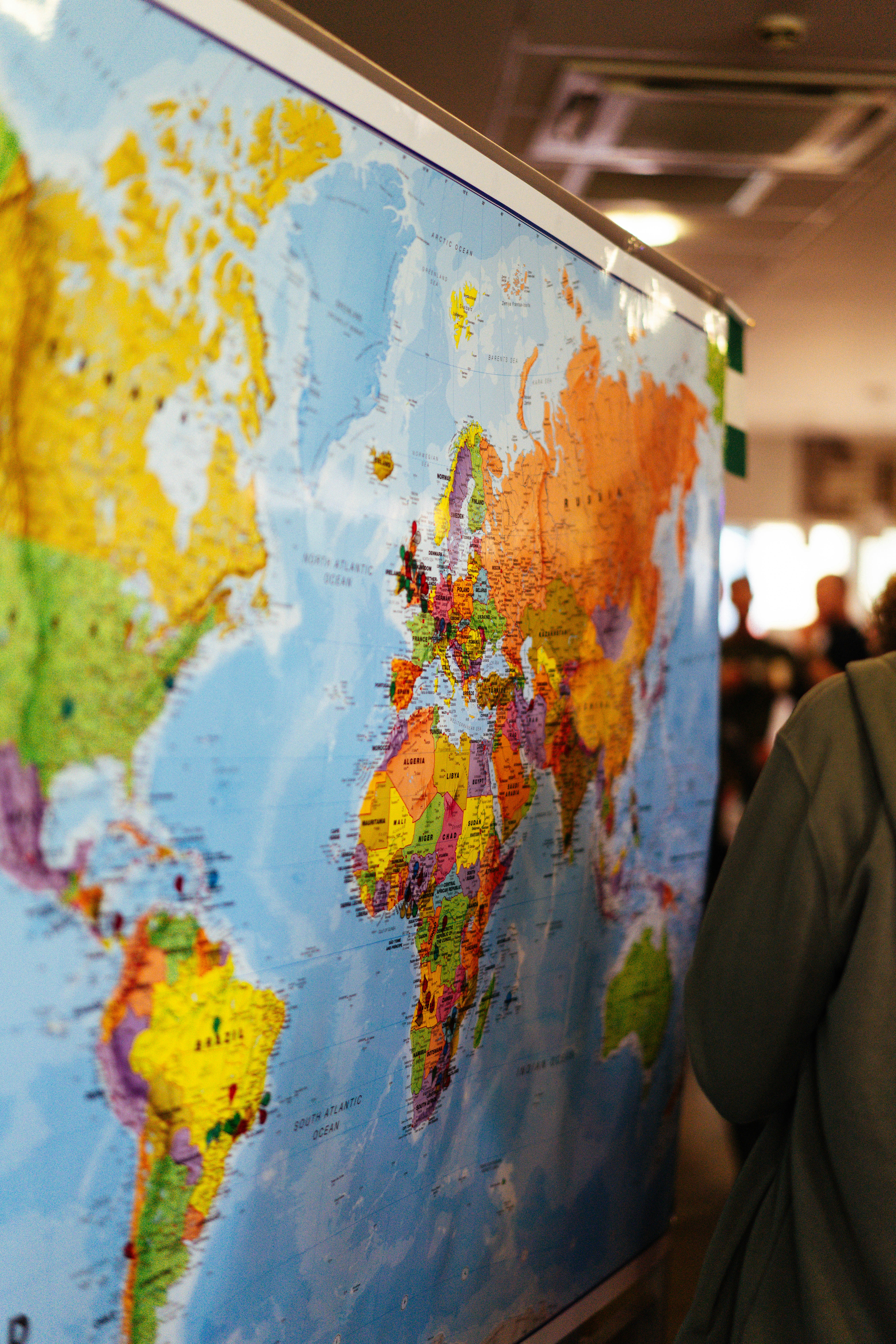 A person looks at pushpins on a world map.