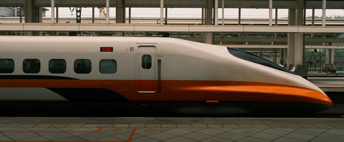 A white Taiwan High Speed Rail train with an orange stripe at the platform of HSR Zuoying Station, Kaohsiung