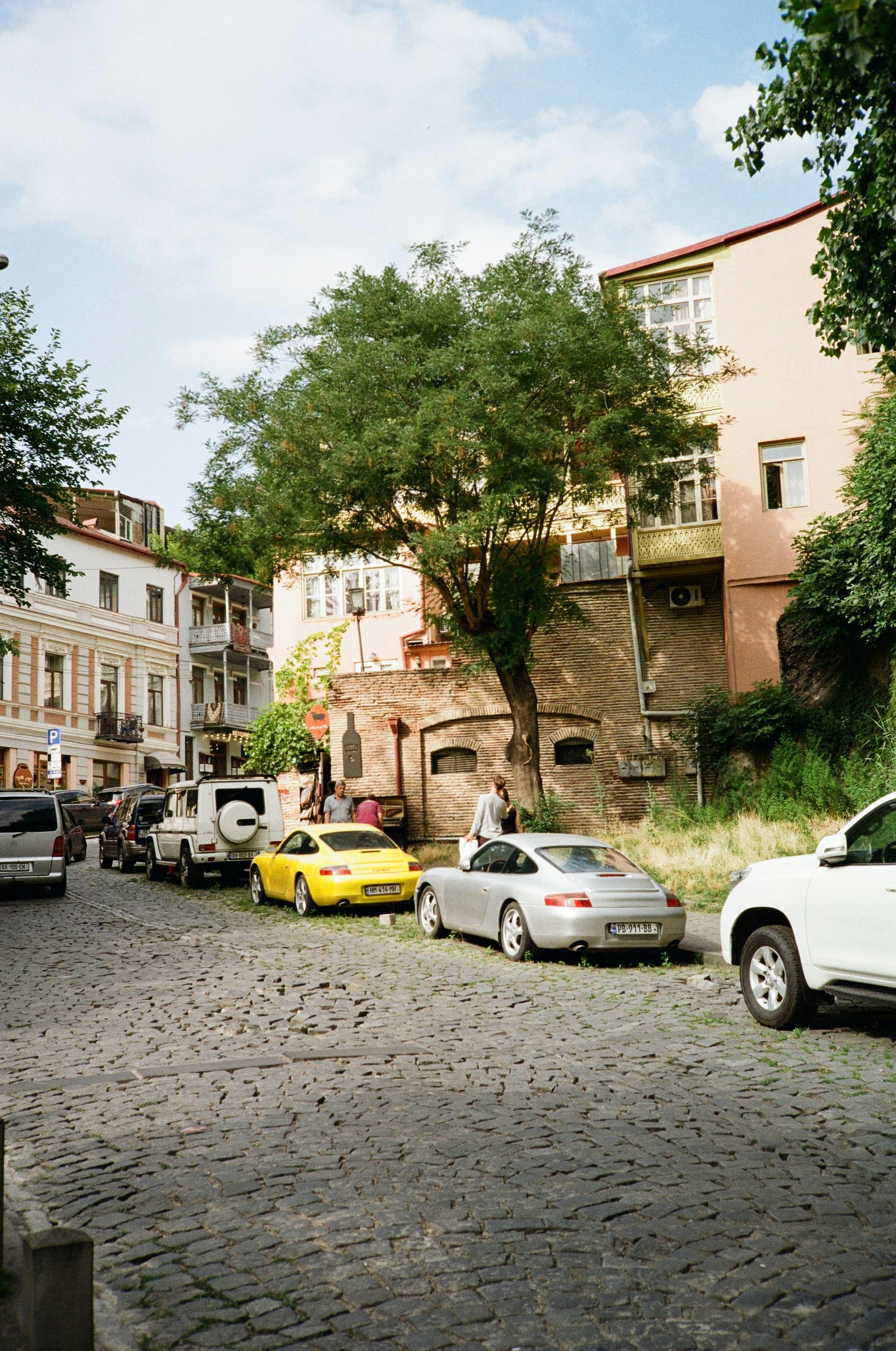 Cars are parked on a cobblestone street.