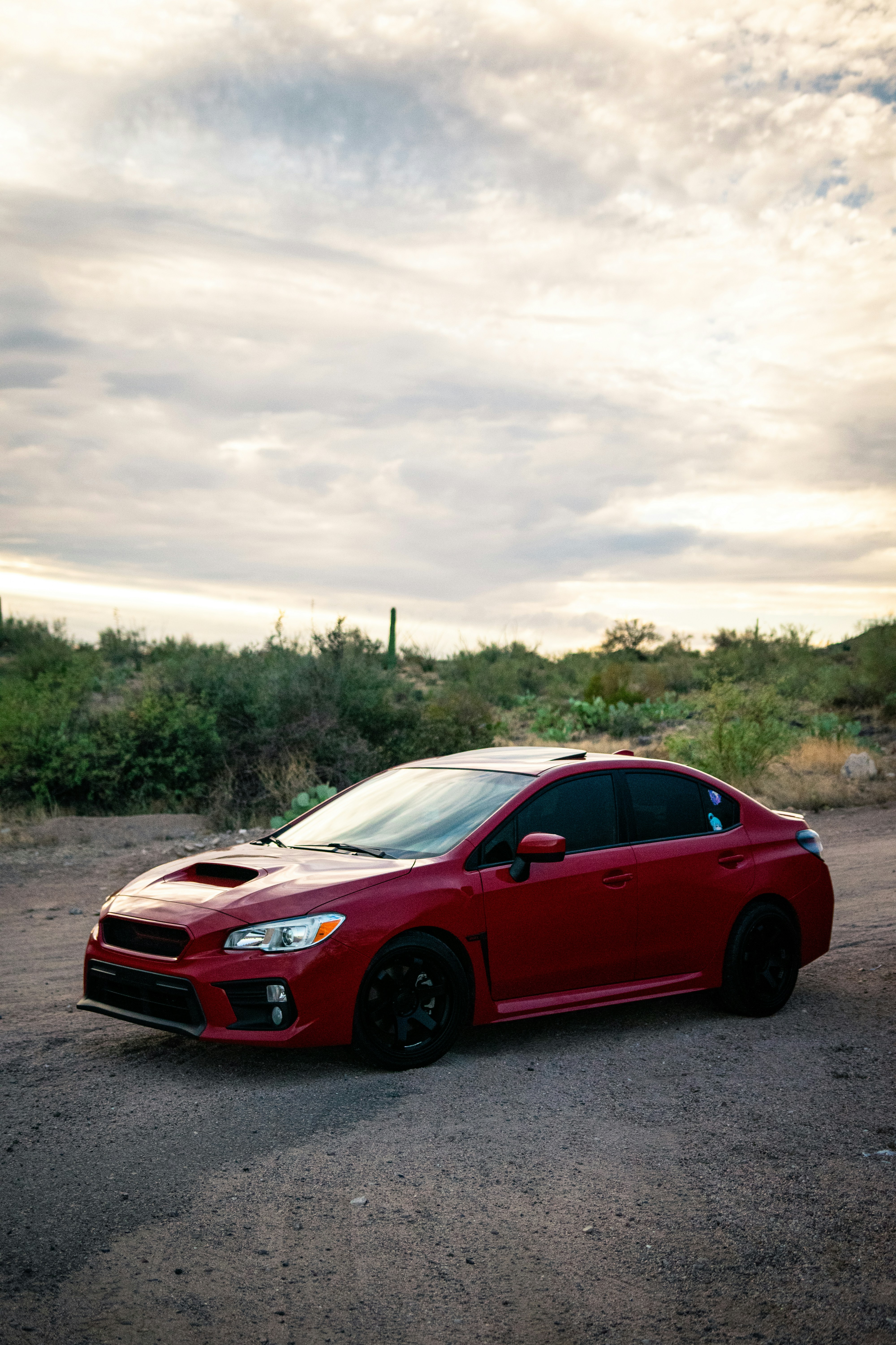 A red subaru wrx sits on a dirt road.