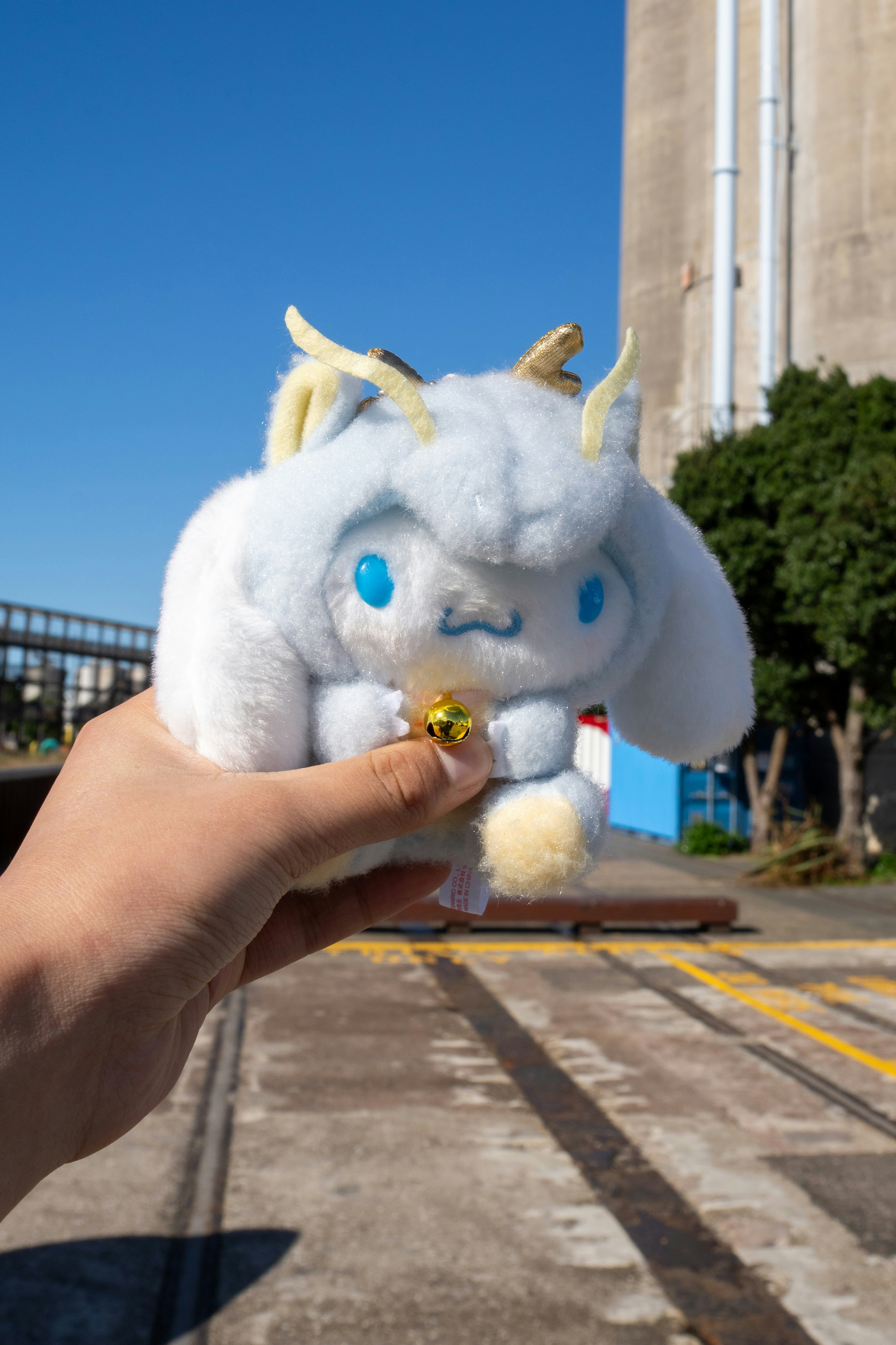 A hand holds a cinnamoroll plush toy.