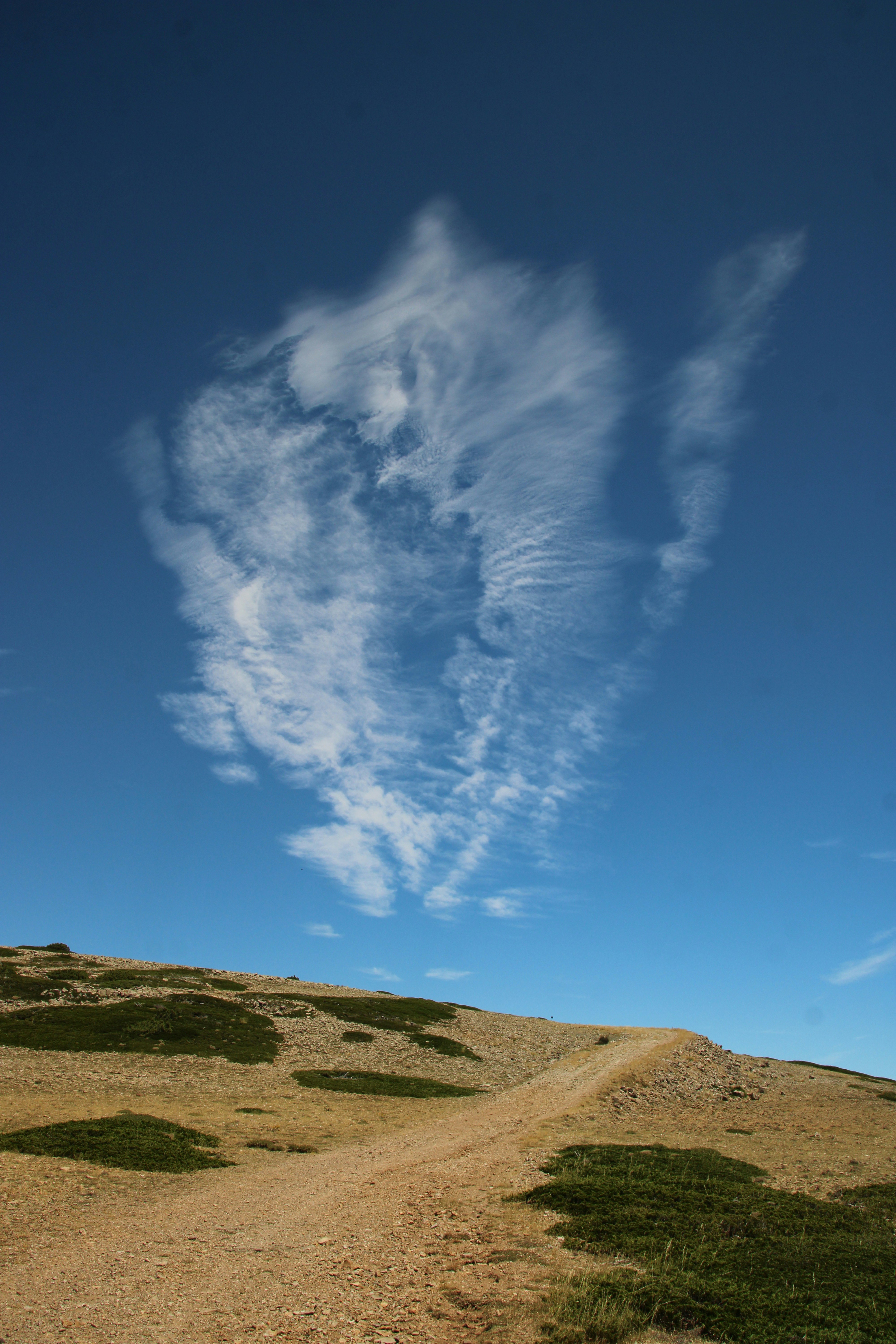 A dramatic cloud floats above a rocky landscape.