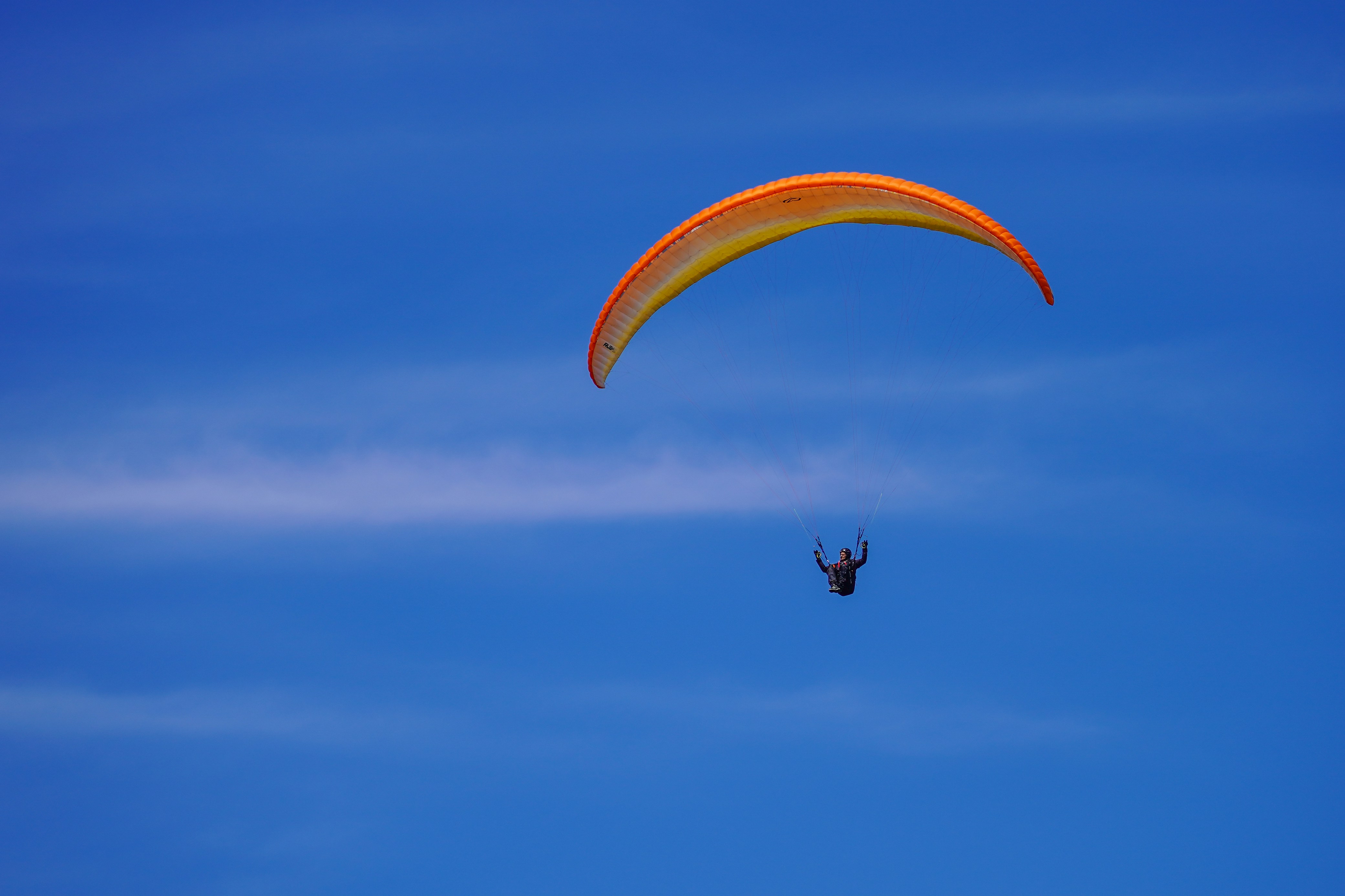 A paraglider soars high above in the sky.