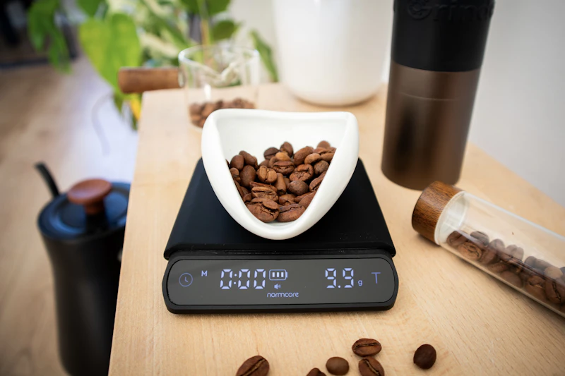 Grains de café pesés dans un bol sur une balance digitale, sur une table en bois