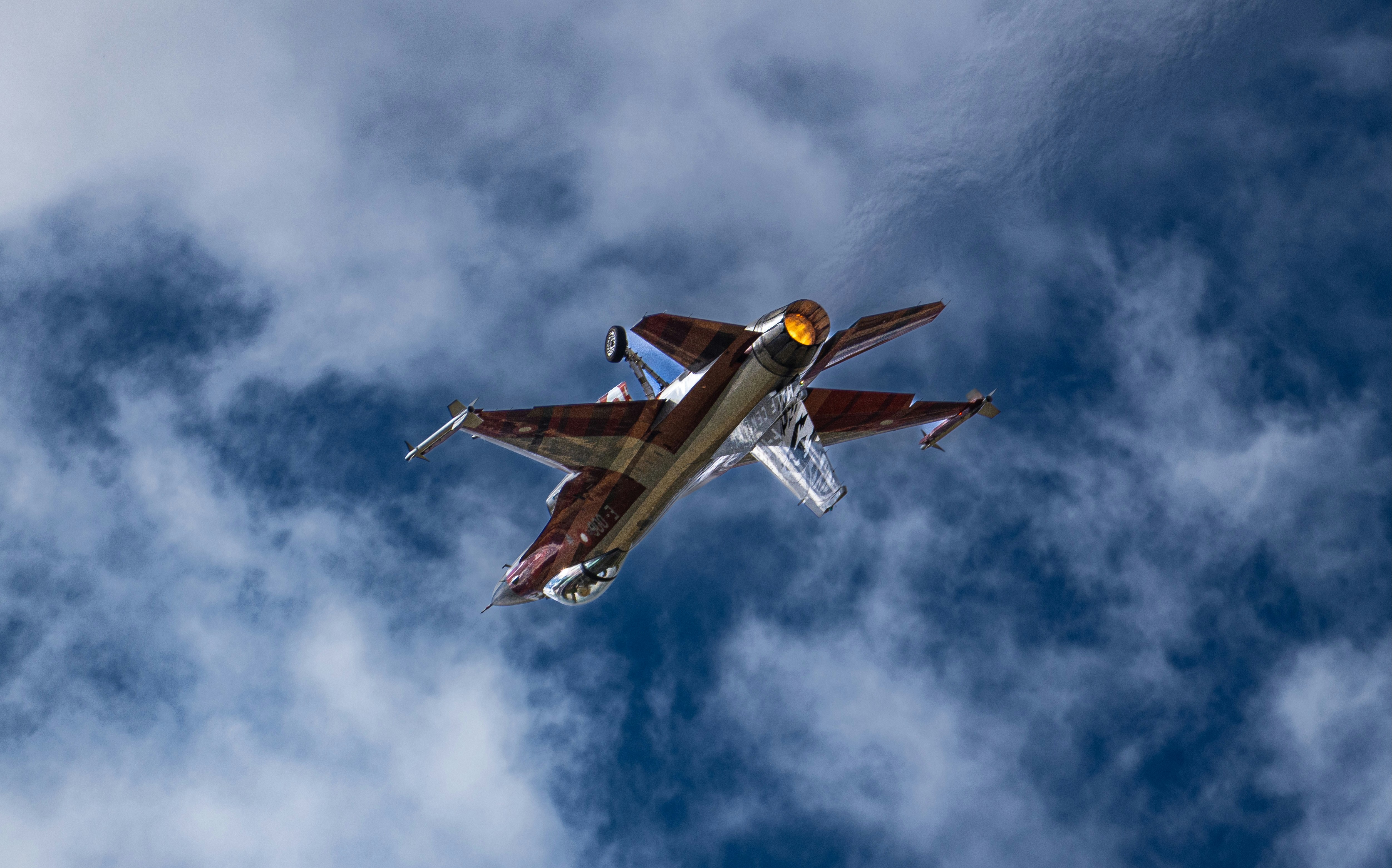 A fighter jet soars through a cloudy sky.