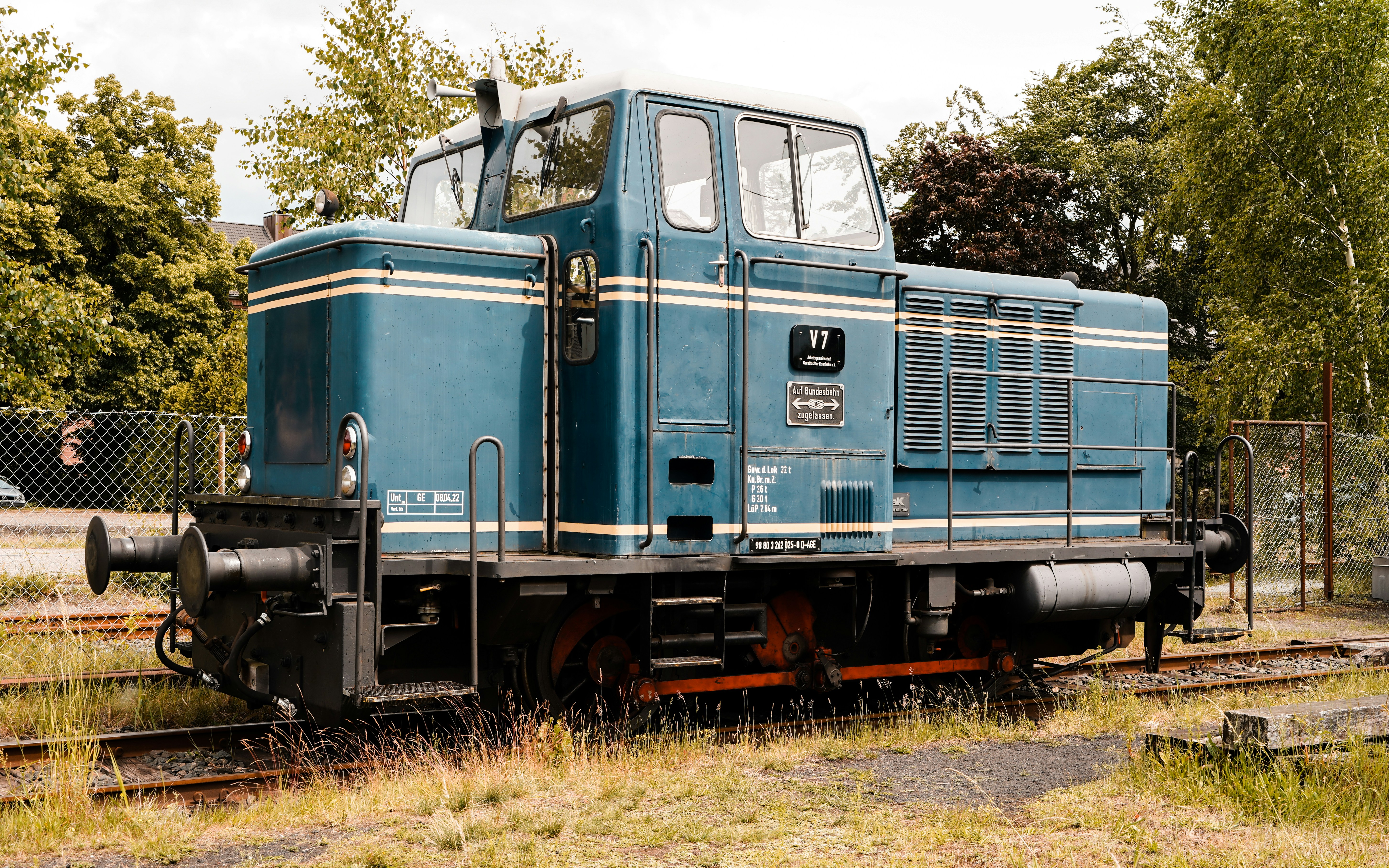 A blue train is parked on railroad tracks.