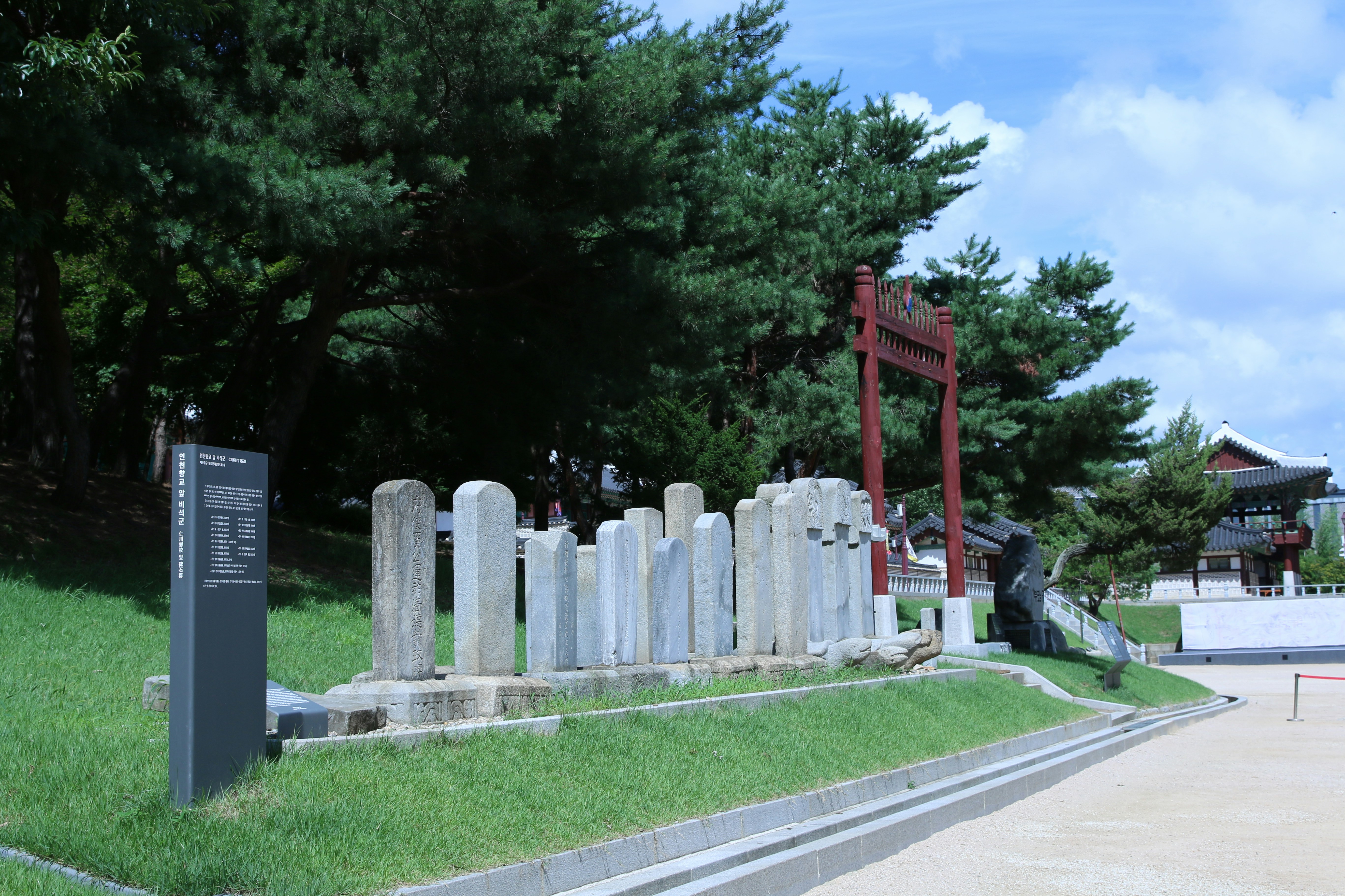 Stone pillars line a pathway with an arch in the background.