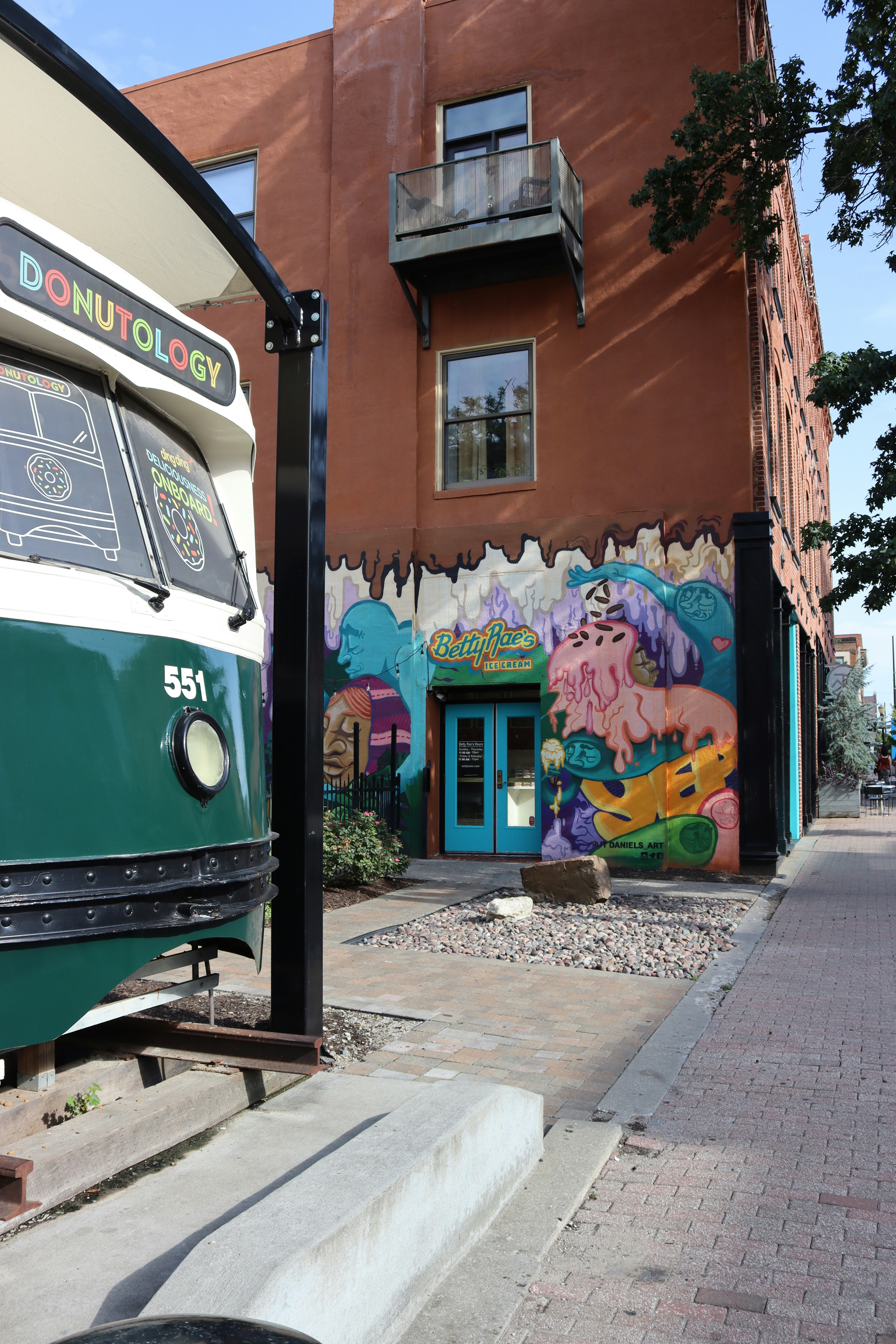 A loja de donuts está localizada ao lado de um bonde antigo.