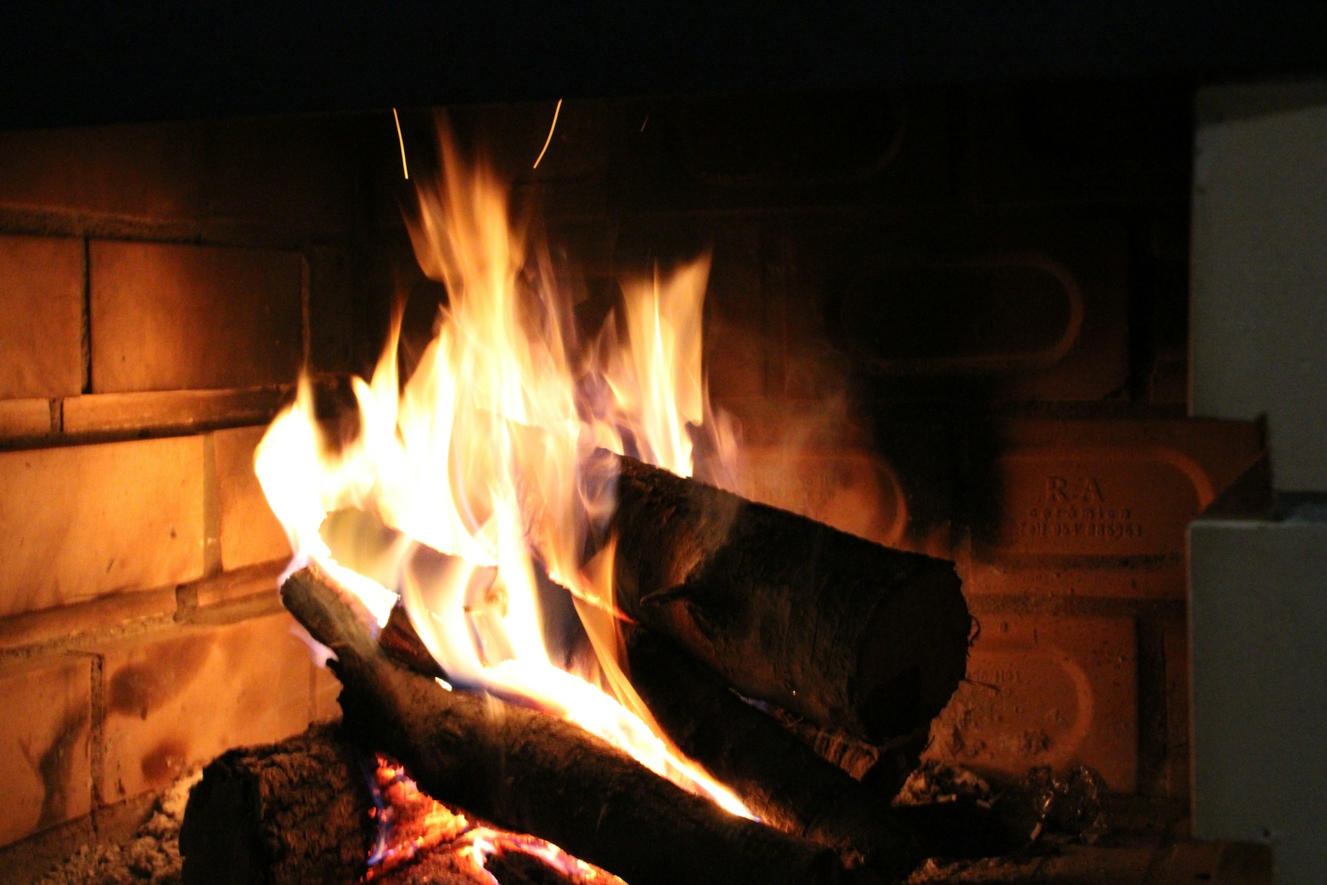 Firewood is burning brightly in a fireplace.