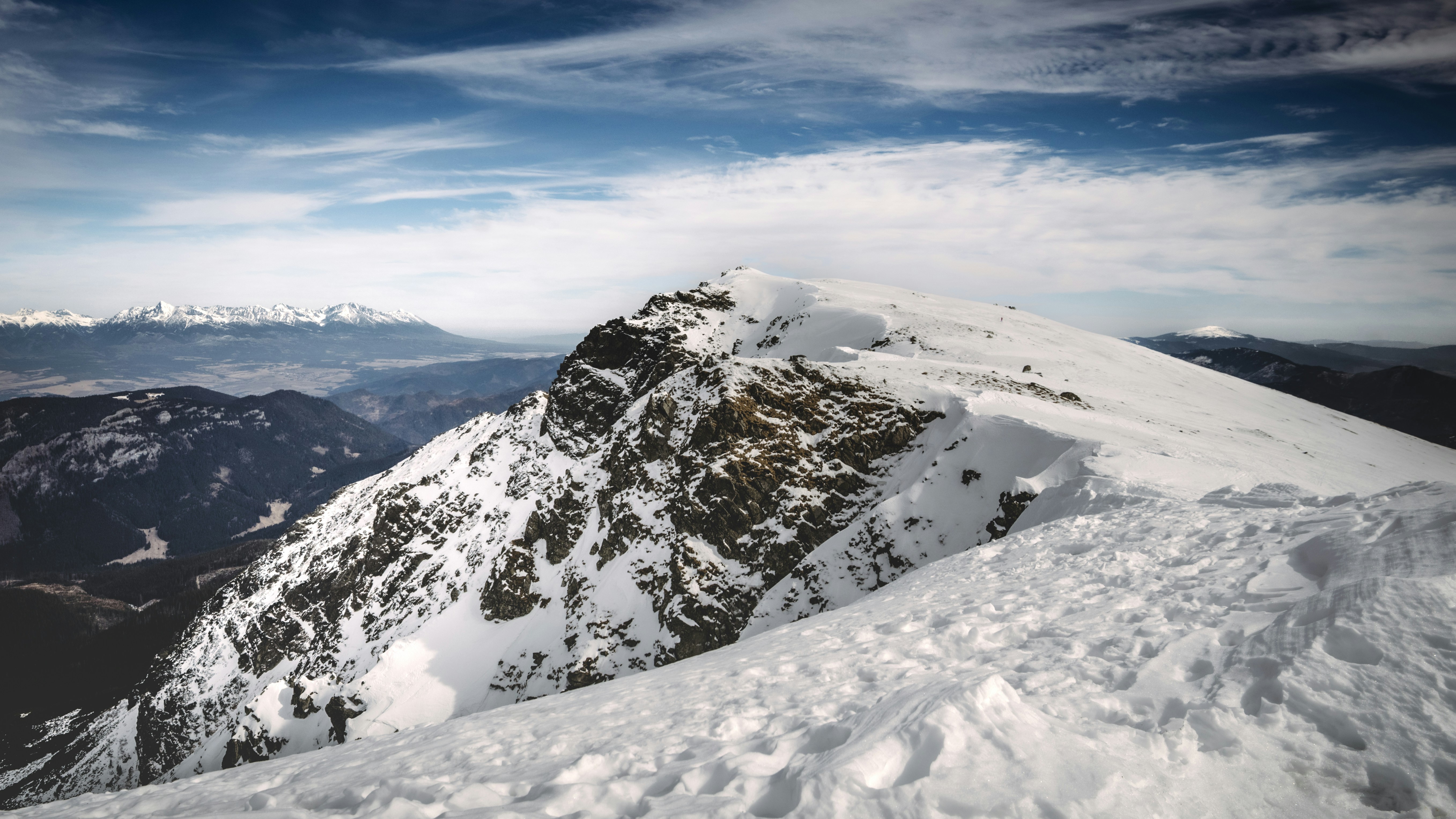 Snow-covered mountain peaks reach towards a blue sky.