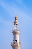 A mosque minaret towers against a clear blue sky.