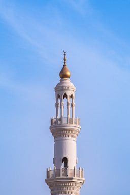 A mosque minaret towers against a clear blue sky.
