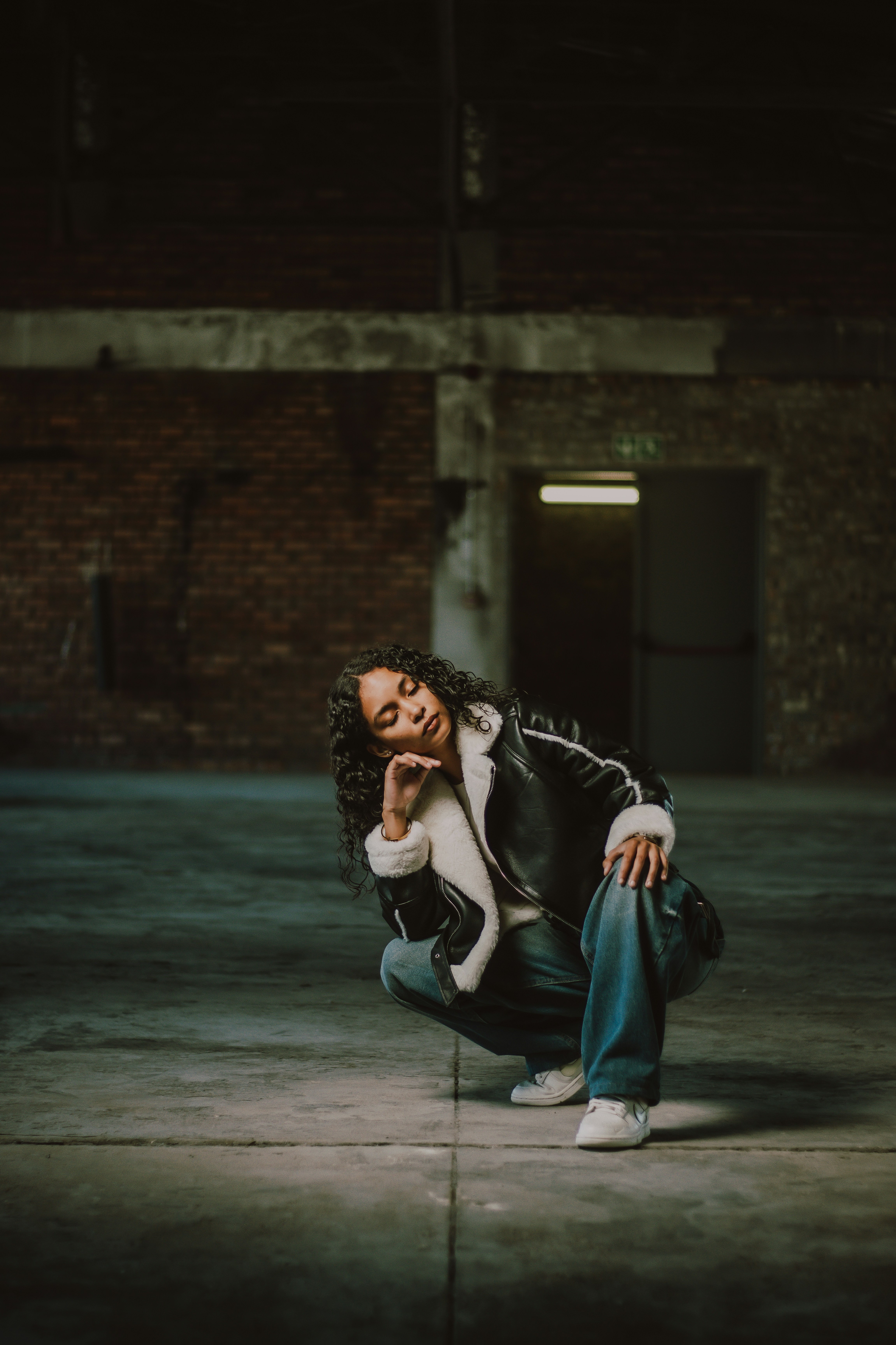 Frau in einem verlassenen Gebäude, hockend und posierend.