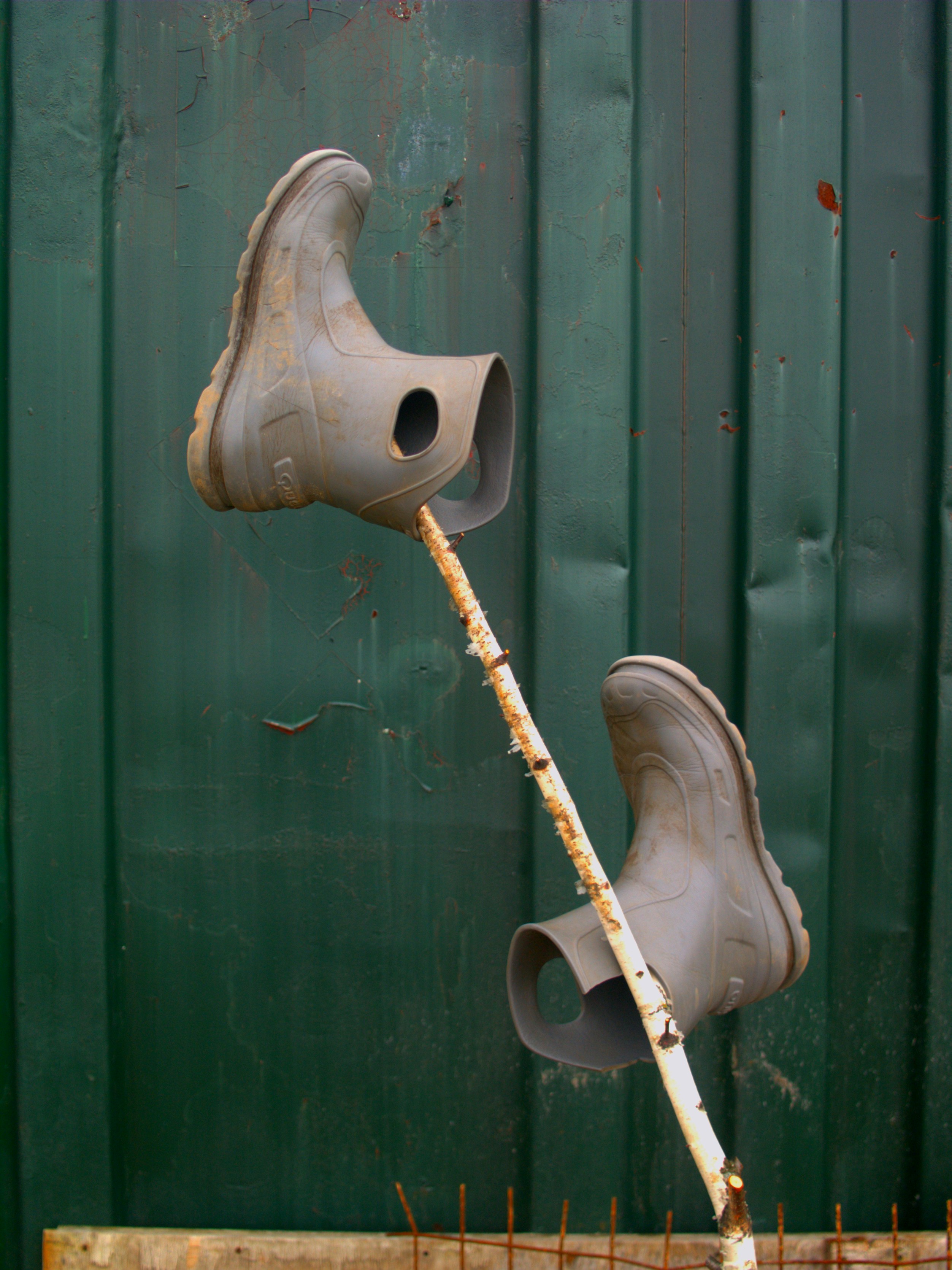 Boots on a stick against a green backdrop.