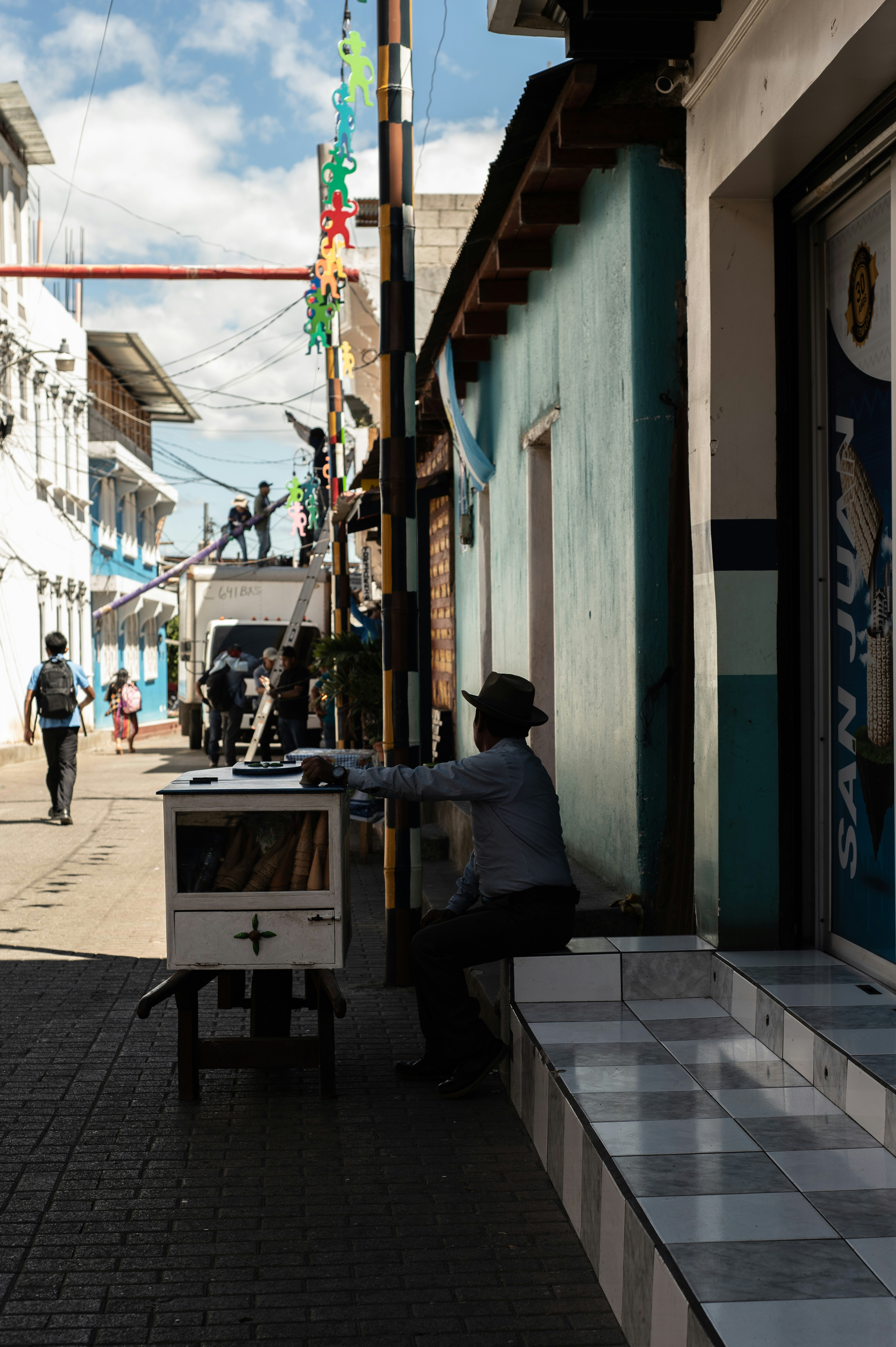 A man sits in front of a street stall.