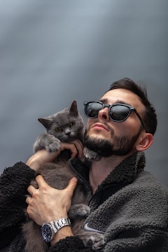 A man holds a gray cat.