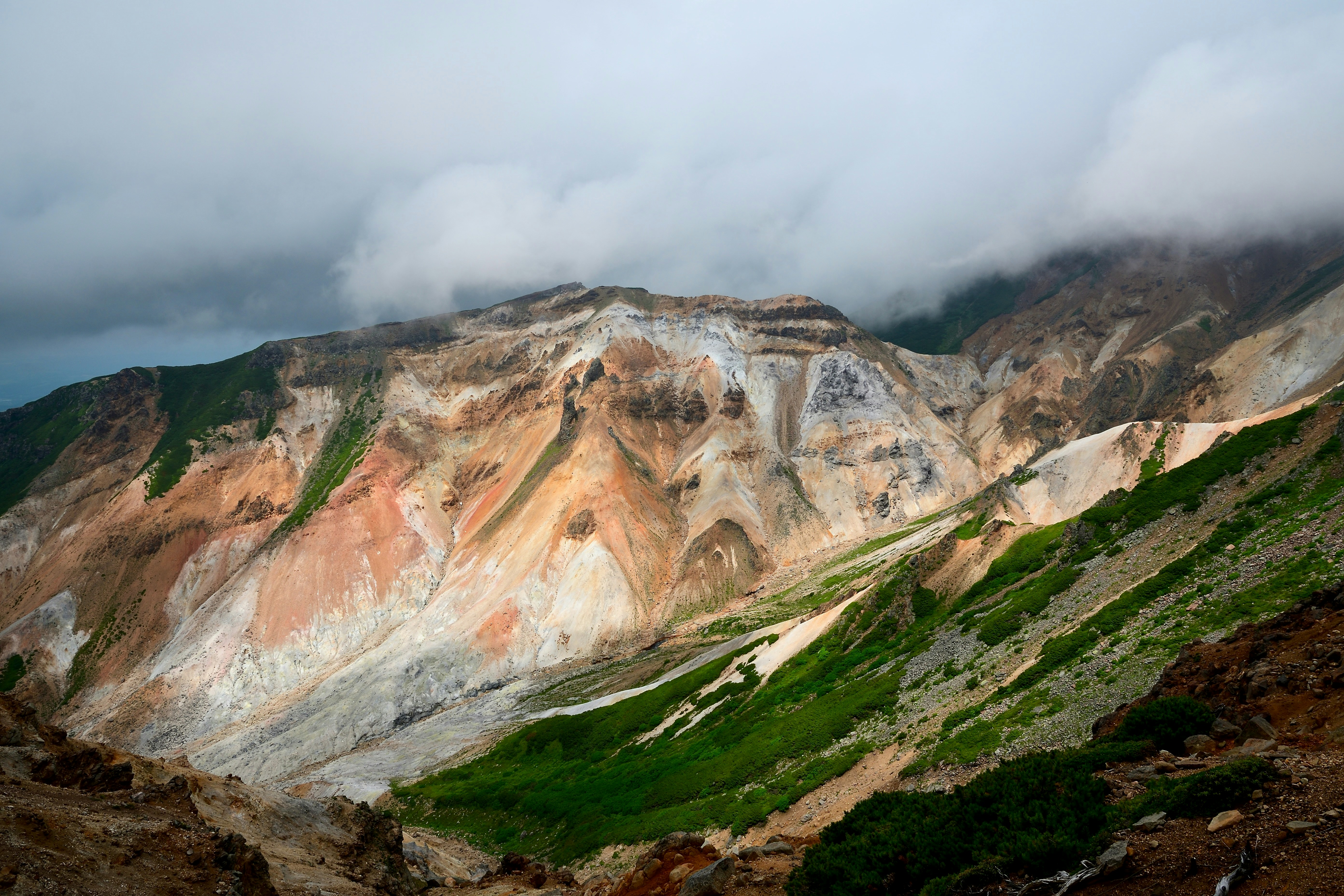 Colorful mountains loom under a cloudy sky.