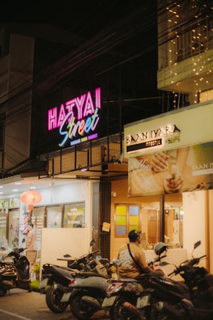 Neon sign illuminates a street in hat yai, thailand.