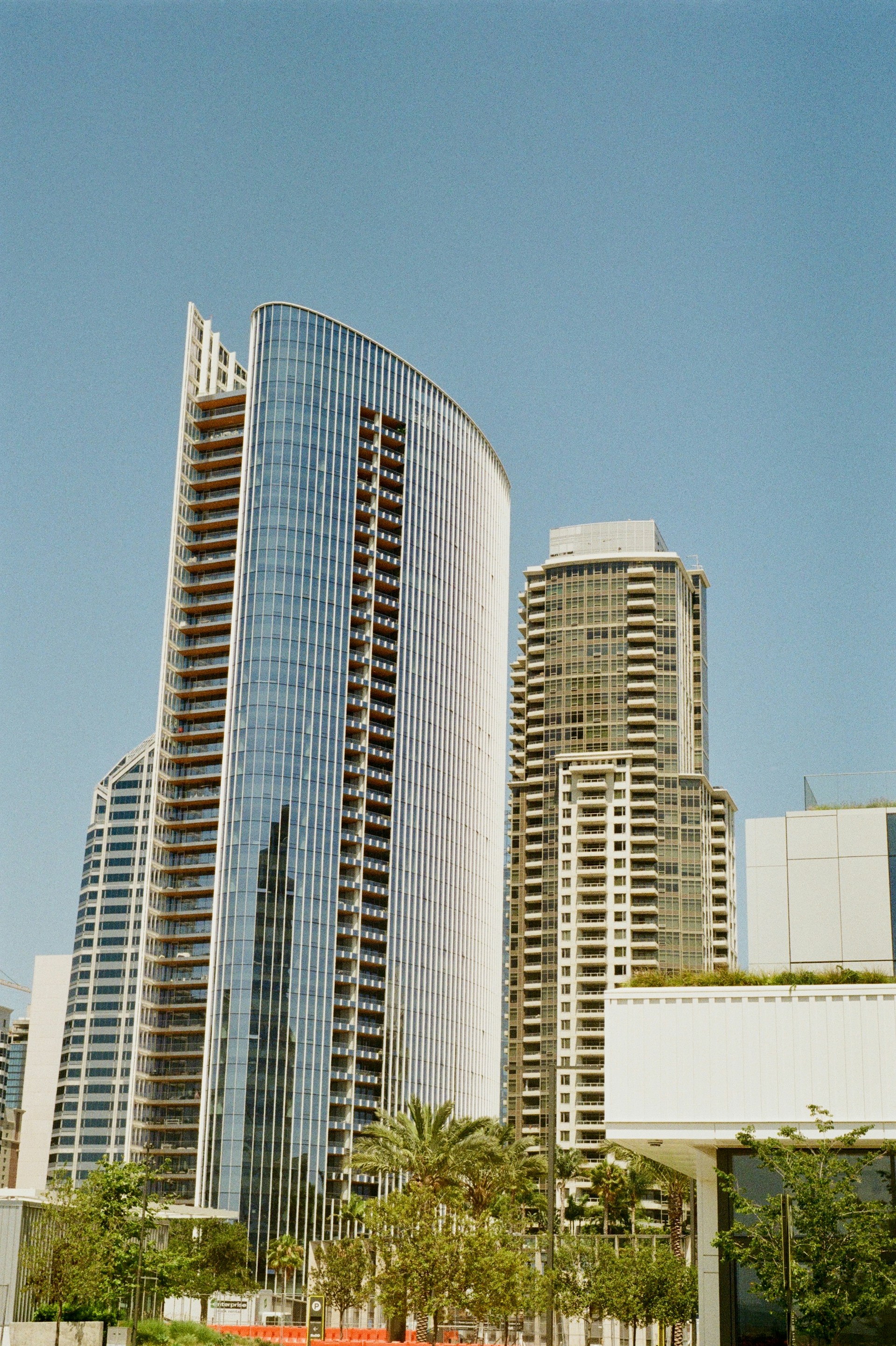 Modern skyscrapers stand tall against a bright blue sky.