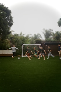 People are playing soccer on the green lawn.