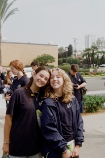 Two smiling friends pose for a photo outdoors.
