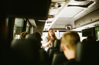 A tour guide is talking to the bus passengers.