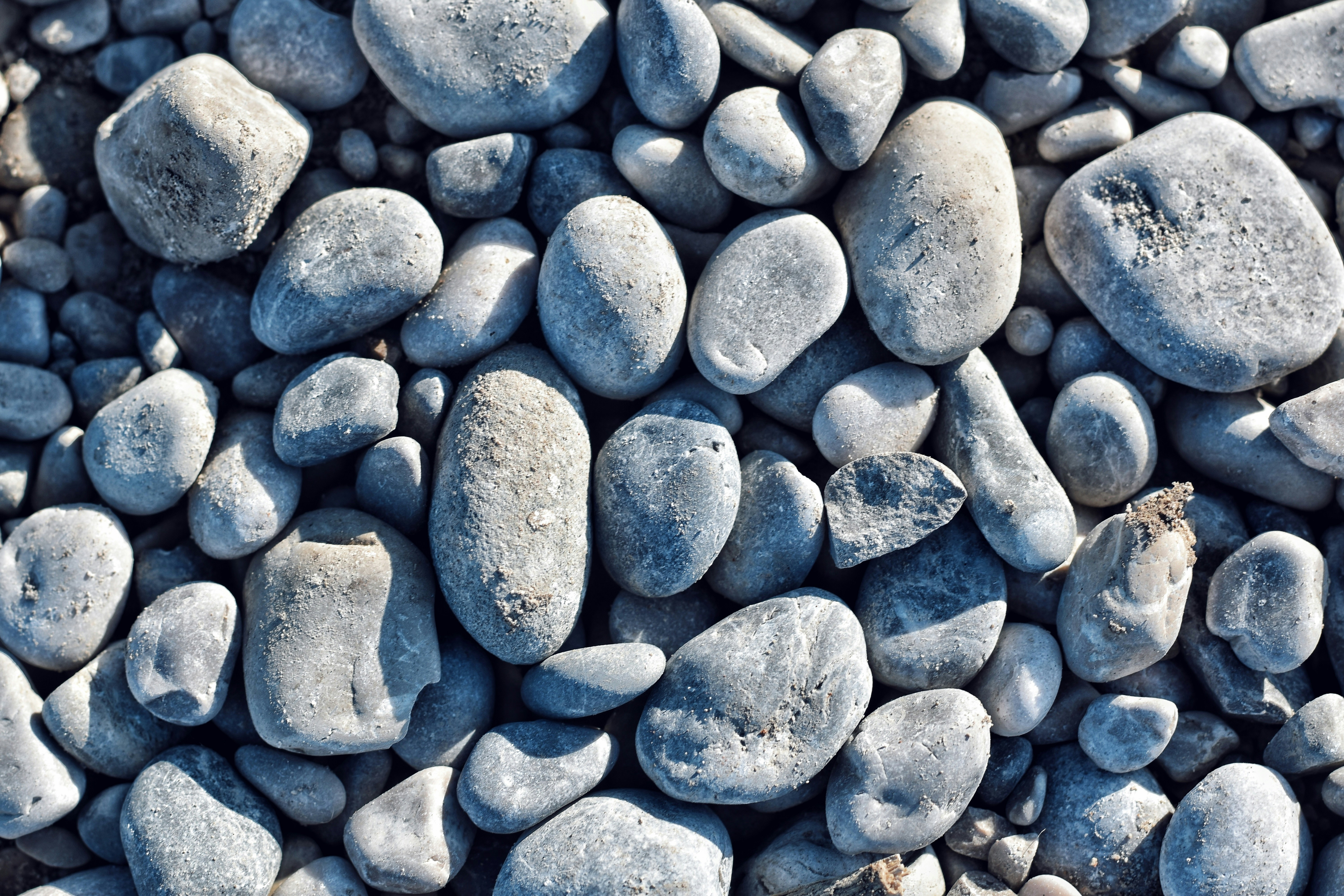 Smooth, round stones cover a sandy surface.