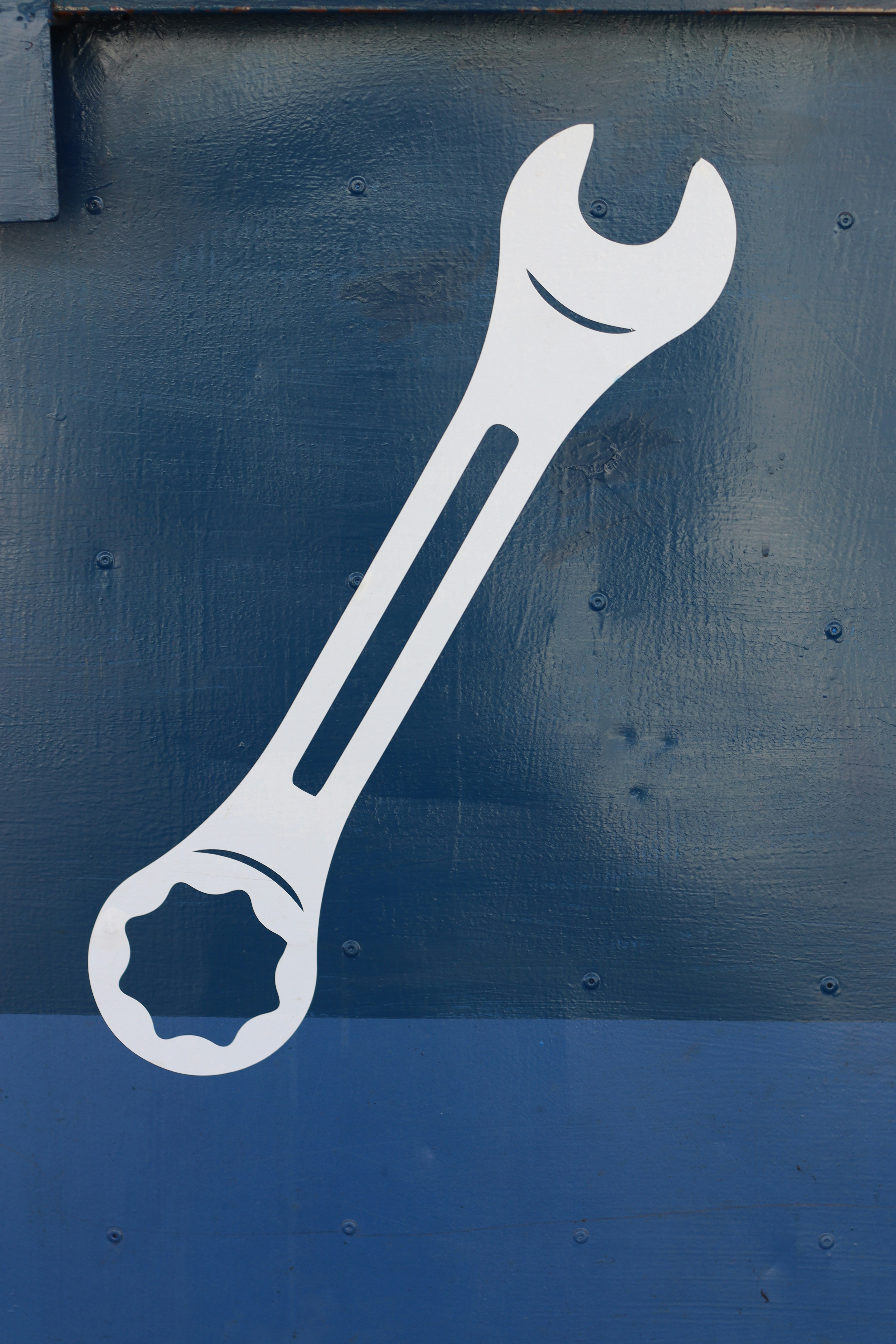 A white wrench is painted on a blue surface.