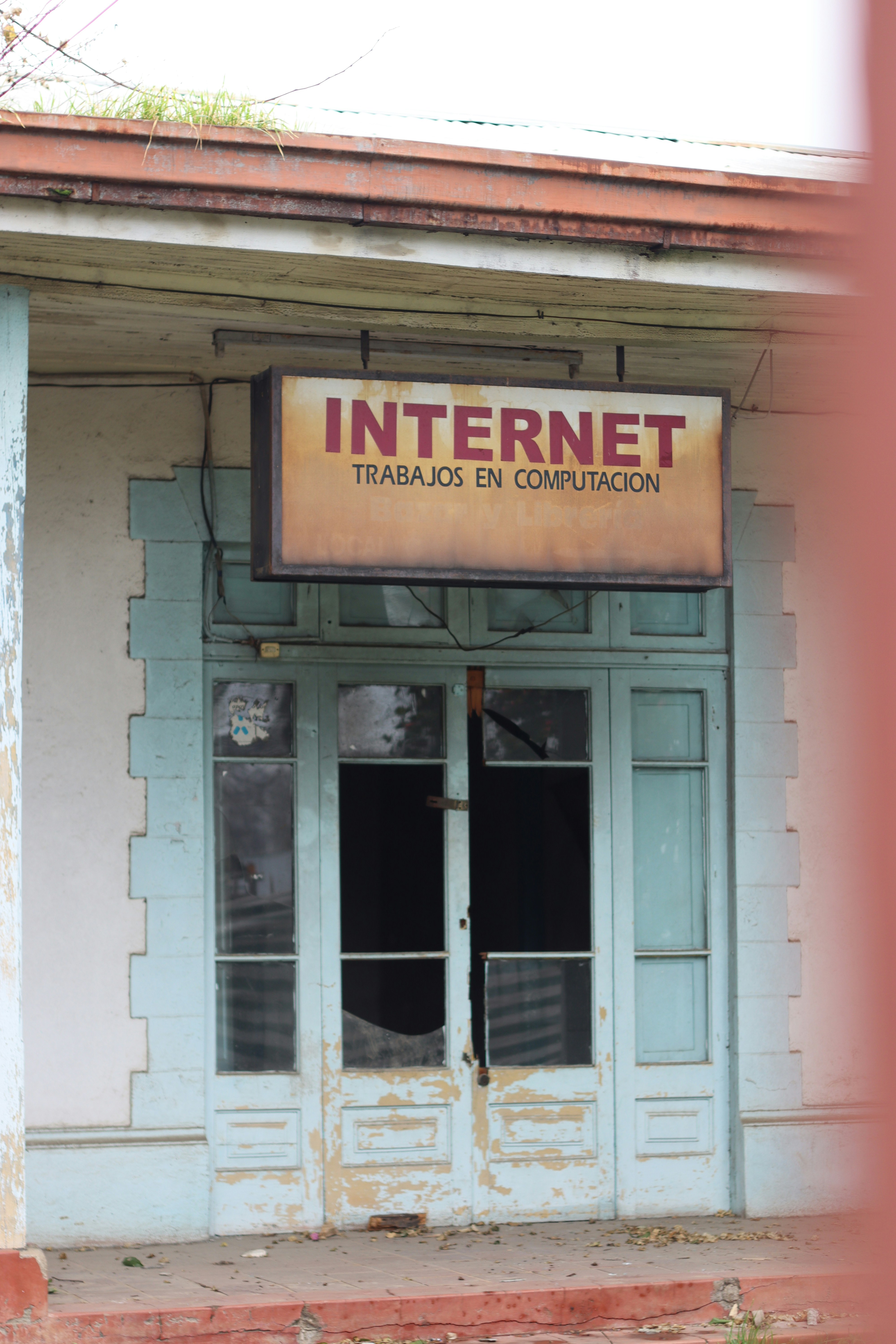 Old, broken door reads "internet" and "trabajos en computación".