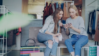 Two women are looking at a phone in a store.