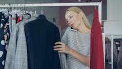 Femme au telephone choisissant des vetements dans un magasin