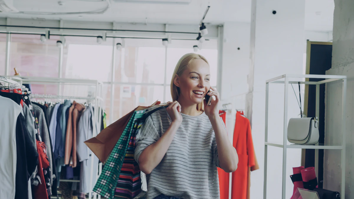 Une cliente souriante, des sacs d'achat à l'épaule, parle au téléphone au milieu des portants d'une boutique de vêtements